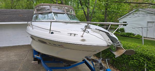1999 Sea Ray 280 SS boat on trailer, parked in driveway near garage and greenery.