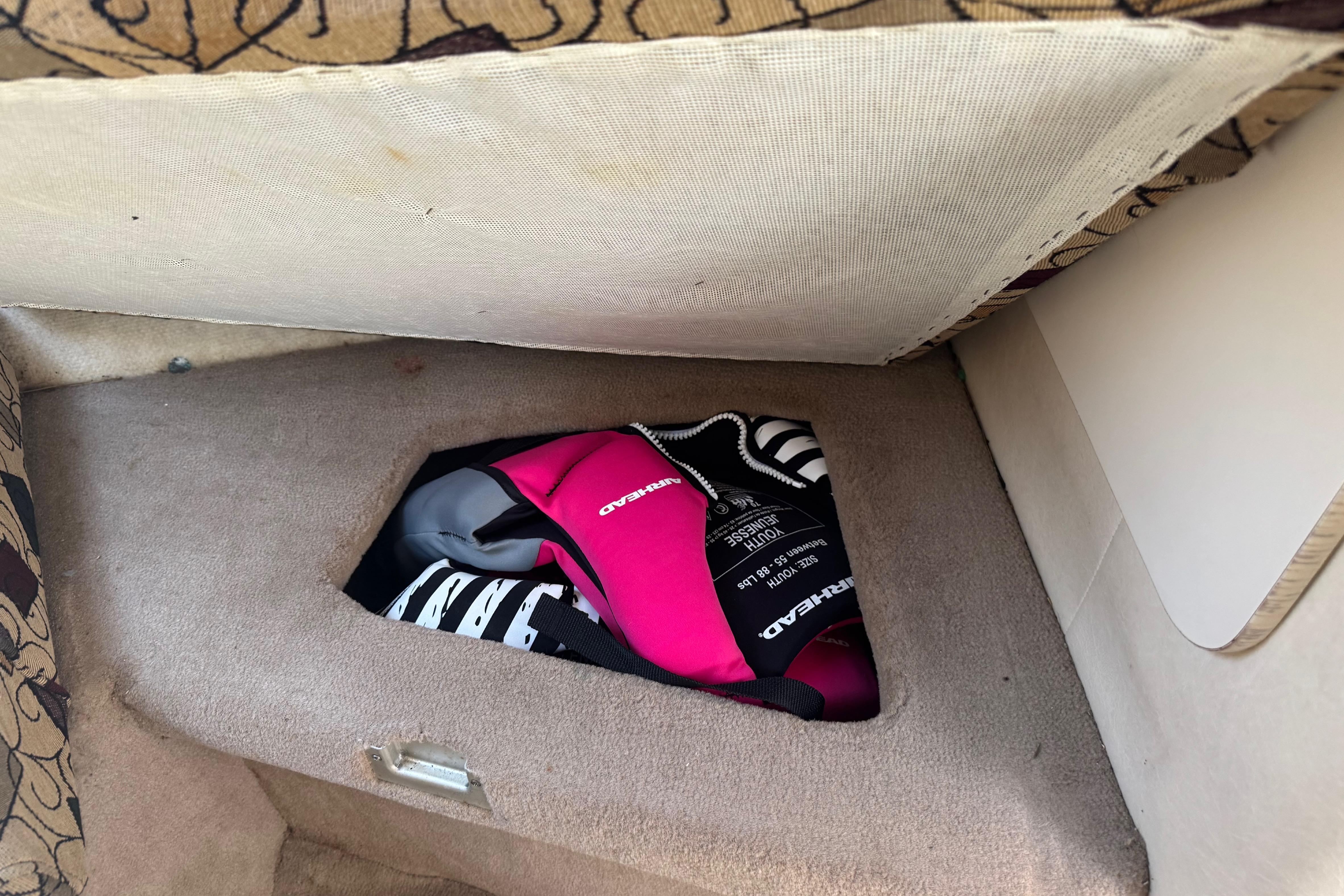 Storage compartment in 2001 Sea Ray 245 Weekender boat with life jackets inside.