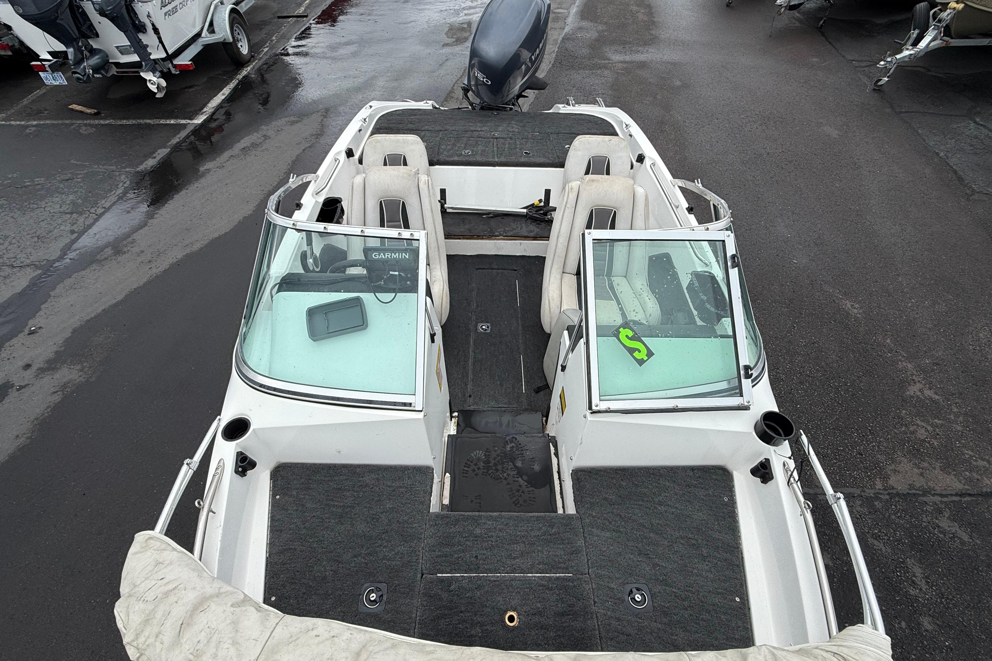 1996 Stratos 283 FS boat interior with seating and windshield, parked on wet pavement.