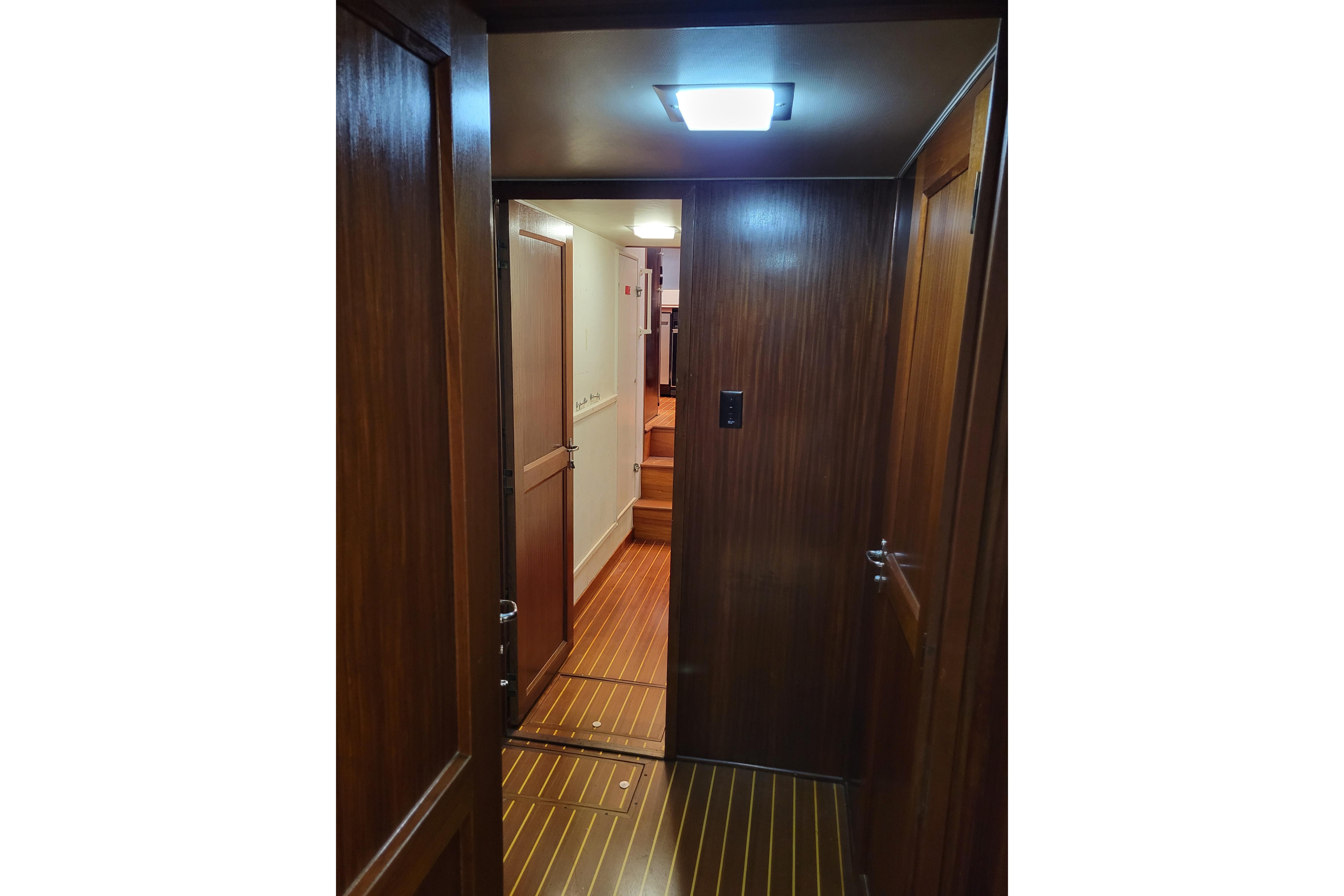 Interior hallway of a 1980 Hatteras 53 Yacht Fisherman with wooden paneling and flooring.
