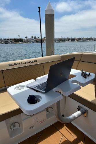 2024 Bayliner DX 2250 boat interior with laptop on table, docked by the water.