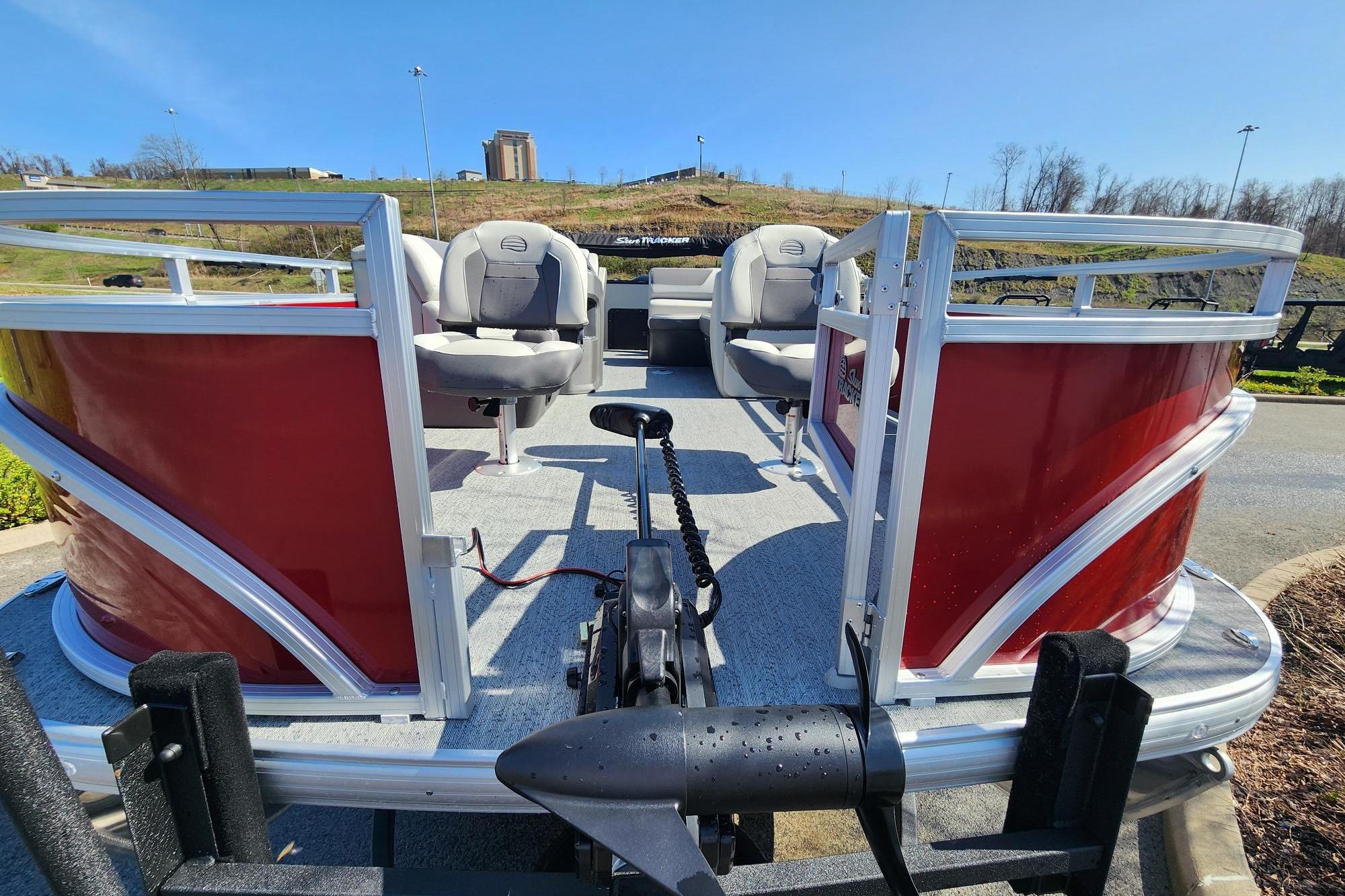 2026 Sun Tracker Fishin' Barge 22 DLX pontoon boat with red exterior and seating.