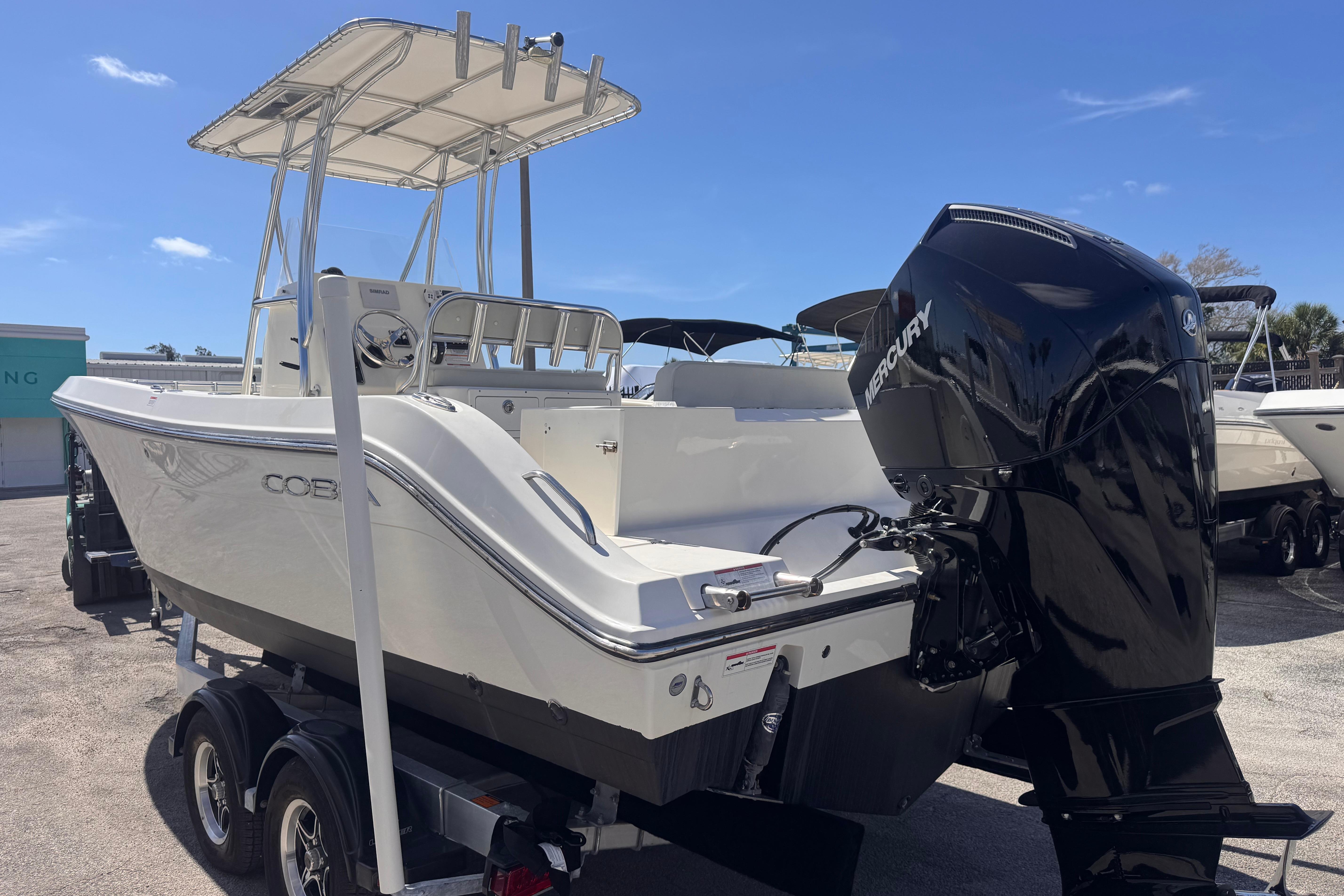2023 Cobia 237 Center Console boat with Mercury engine on trailer, sunny day.