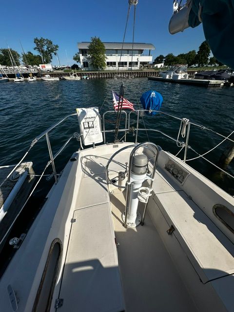 The cockpit of a 1985 Catalina 27 with a steering wheel, overlooking a marina.