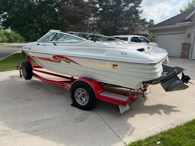 A white 2001 Mariah Shabah boat on a red trailer in a driveway.