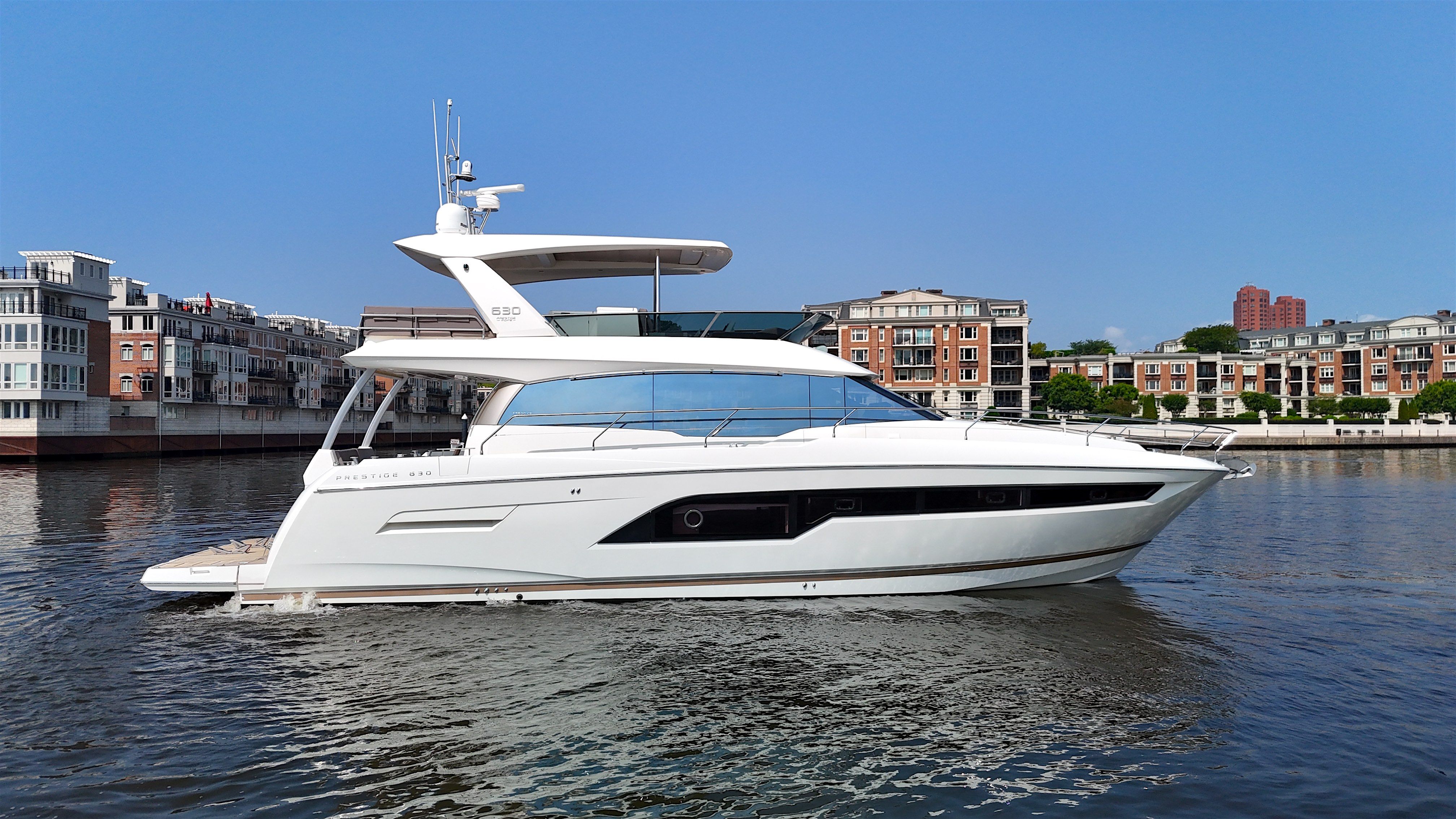 2017 Prestige 630 yacht on calm water near city buildings.