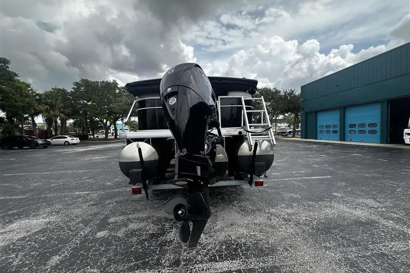 2023 Godfrey 2286 boat with outboard motor in parking lot, cloudy sky background.