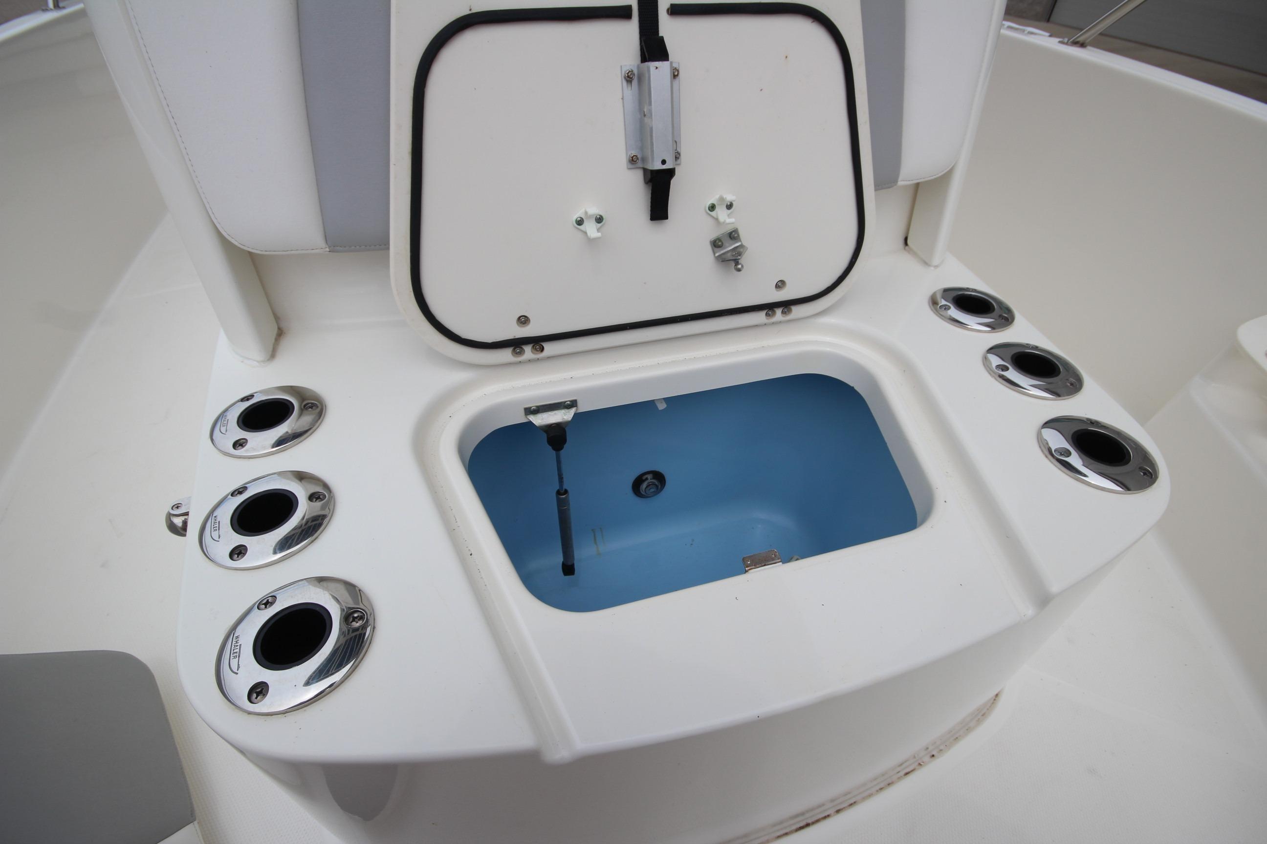 2014 Boston Whaler 210 Dauntless boat storage compartment with rod holders and open hatch.