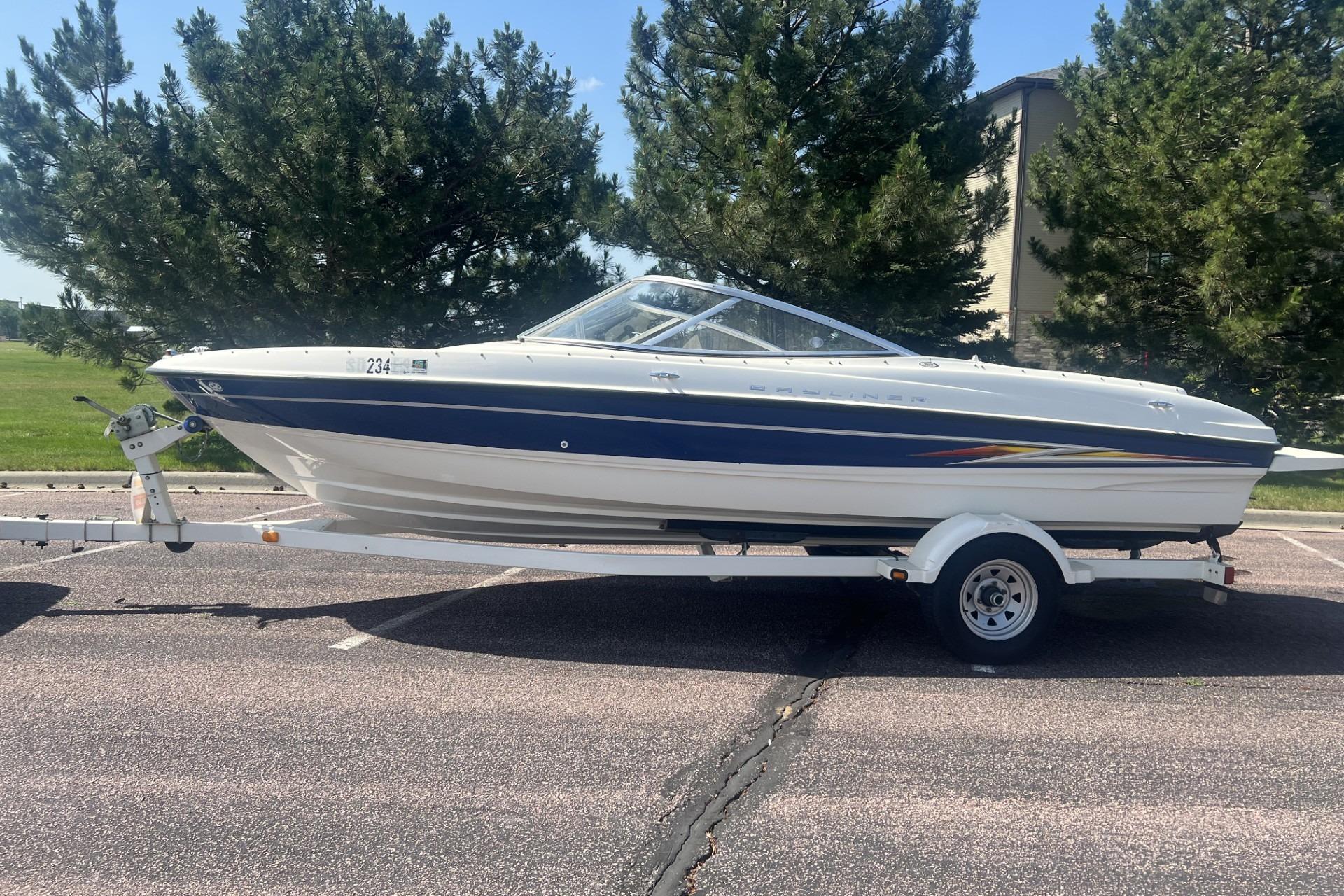 2005 Bayliner 205 Bowrider boat on trailer, parked outdoors with trees in background.