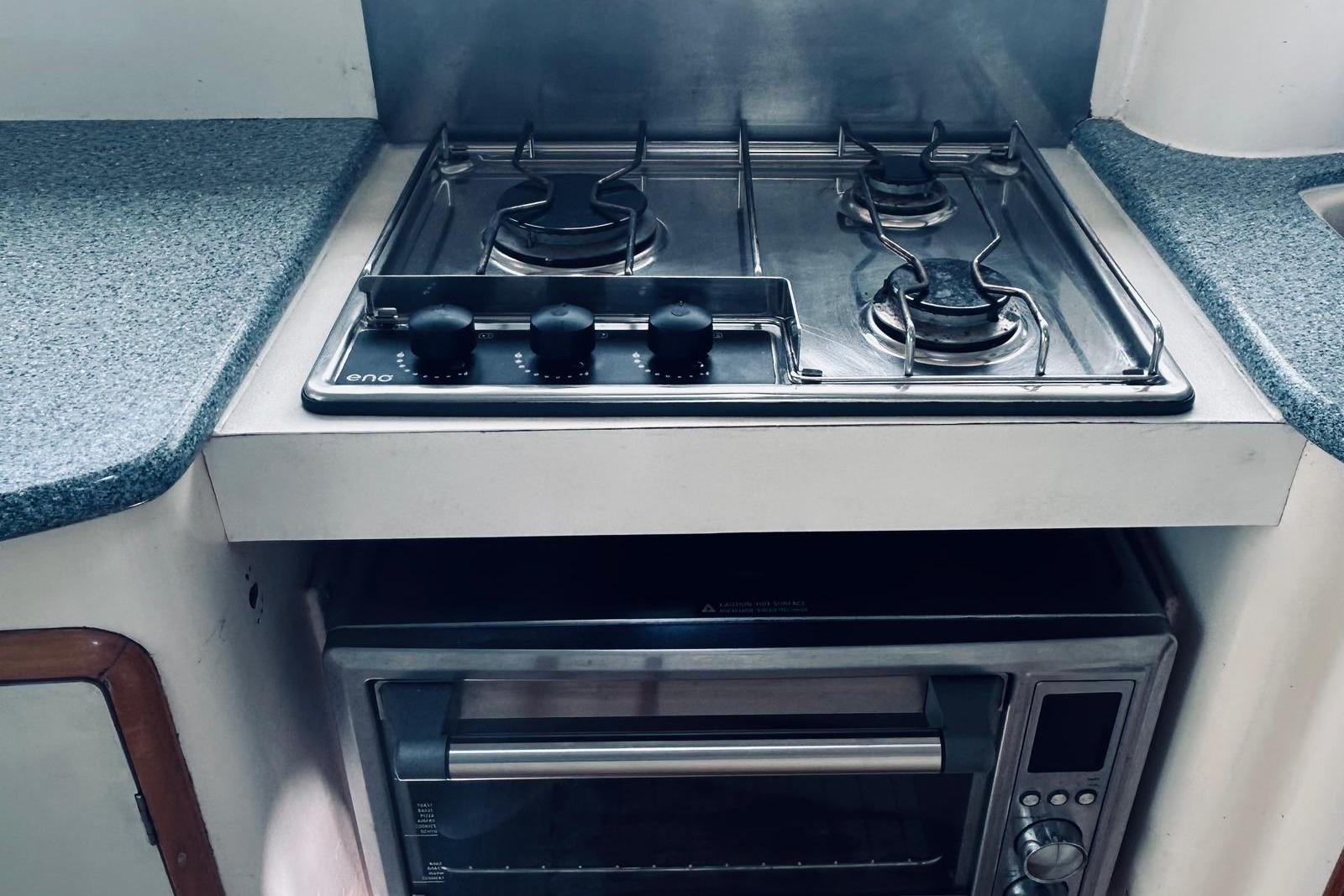 Compact kitchen area with a stainless steel stove and oven on a 2001 Leopard yacht.
