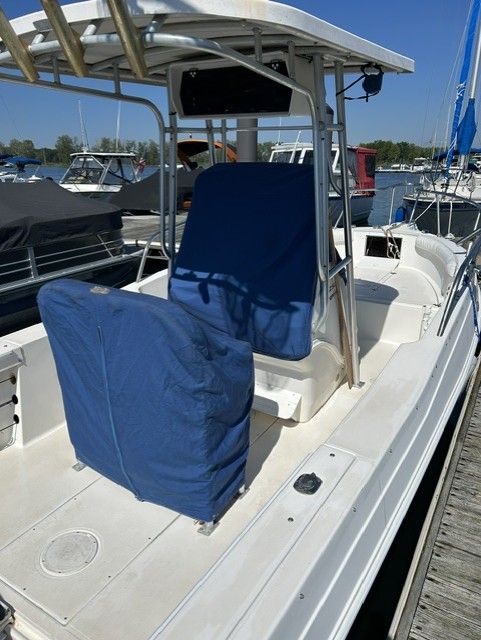 A 2000 Aquasport Osprey 250 docked at a marina, featuring blue seat covers and a T-top.