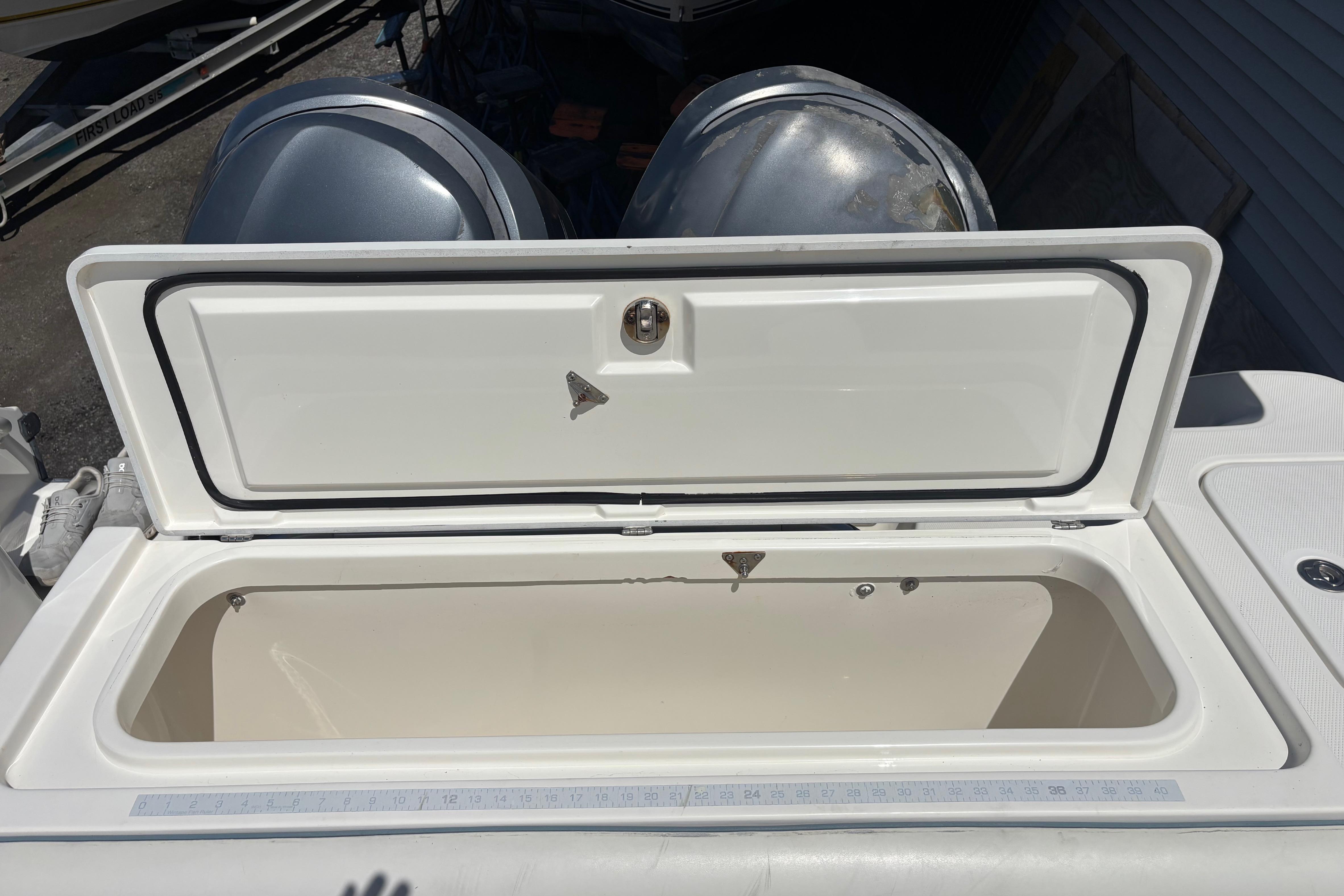 Open storage compartment on a 2006 Edgewater 318CC boat, with visible dual engines.