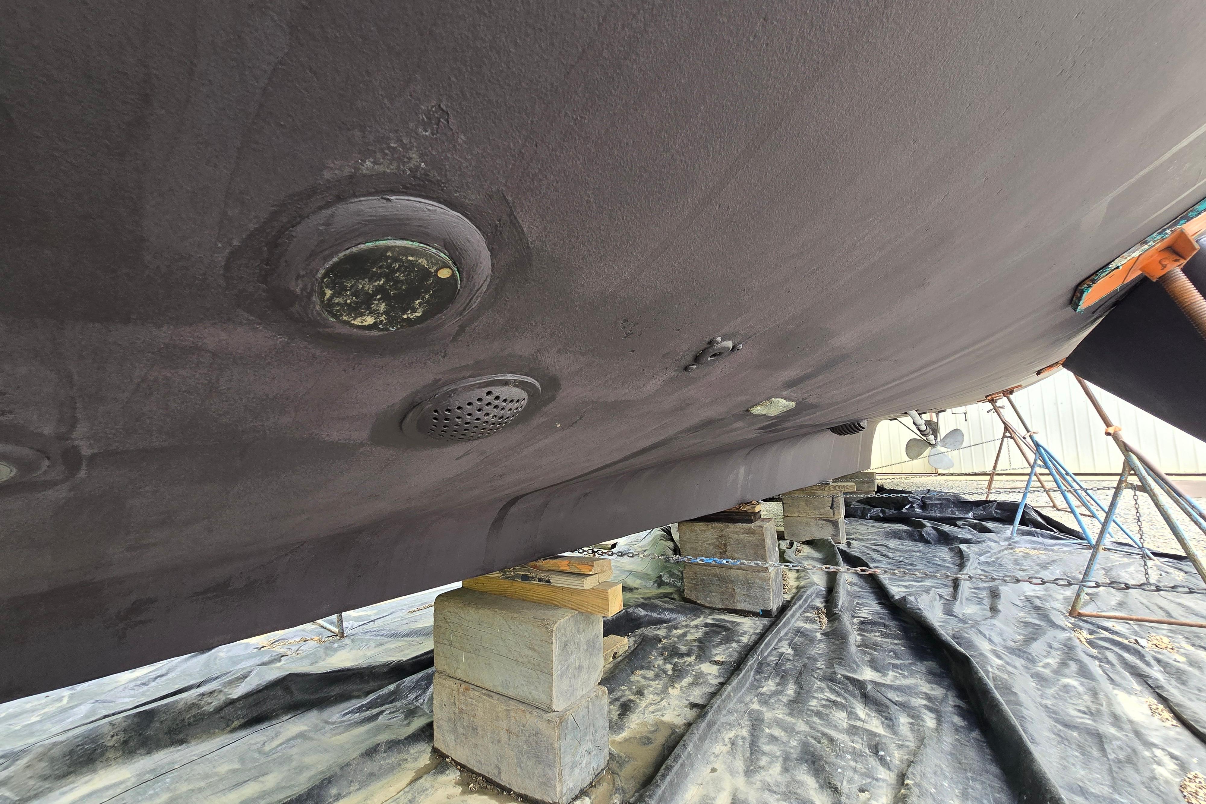 Underside of 1980 Hatteras 70 Motor Yacht on blocks, showing hull details.
