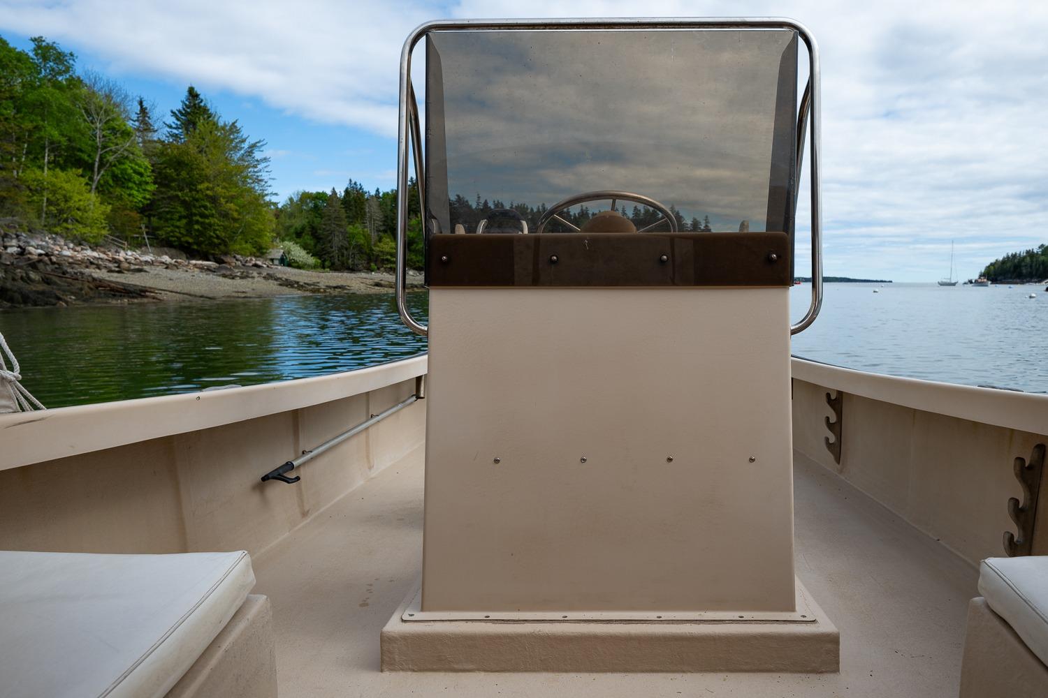 1989 Ellis 24 Open boat on calm water, surrounded by lush greenery and a clear sky.