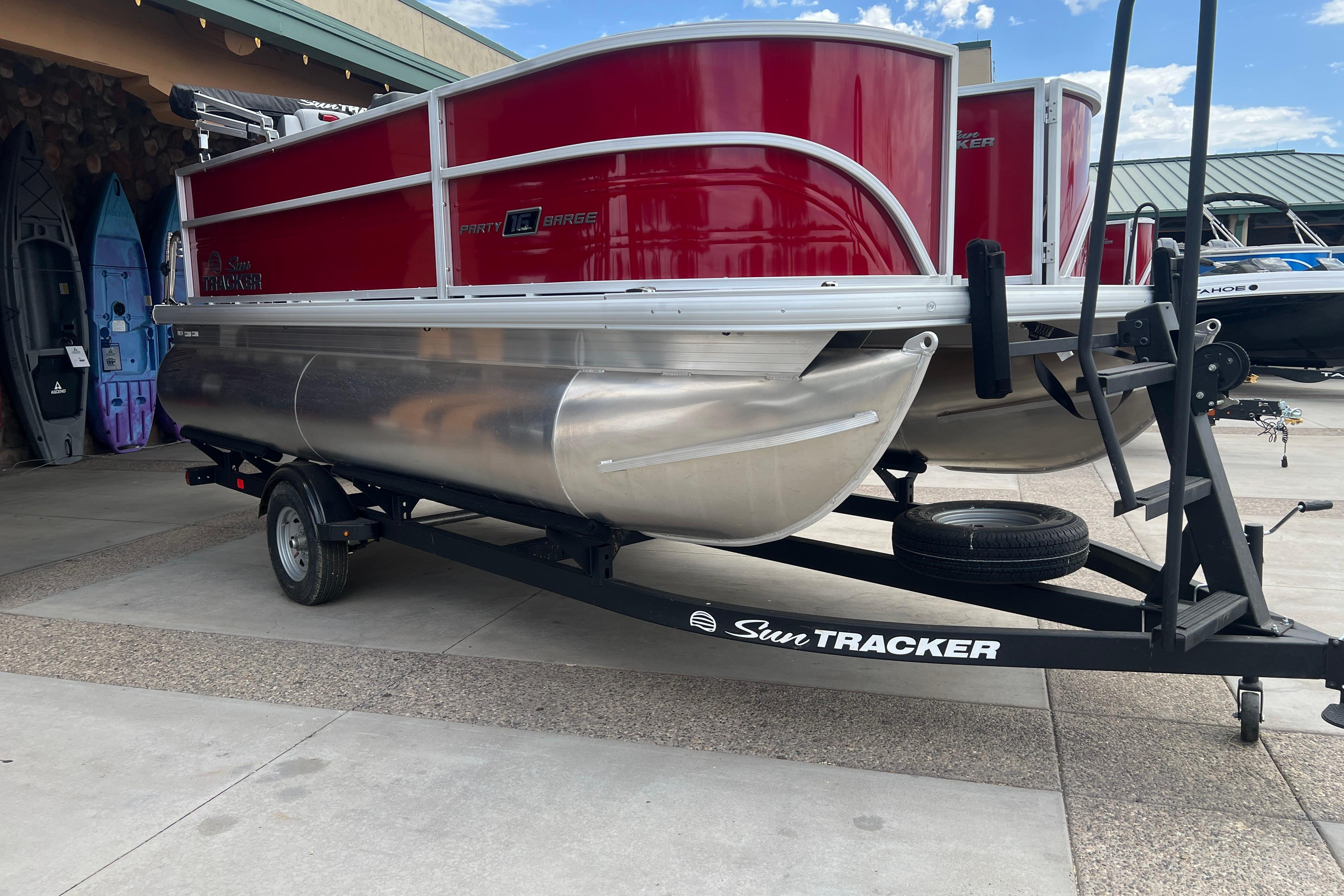 2026 Sun Tracker Party Barge 16 DLX pontoon boat on trailer, parked outdoors.