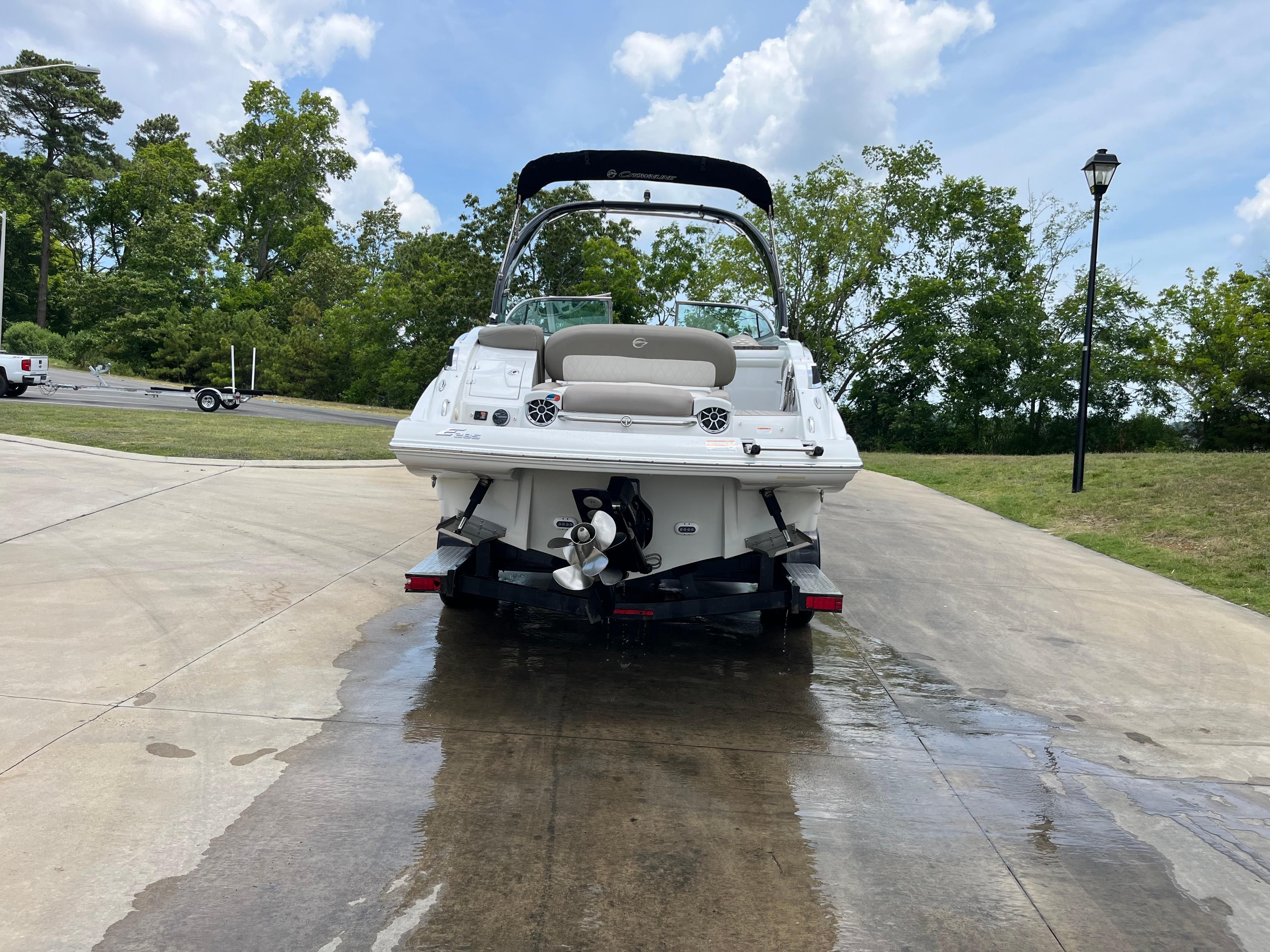 A 2019 Crownline E 285 boat on wet concrete, surrounded by trees.