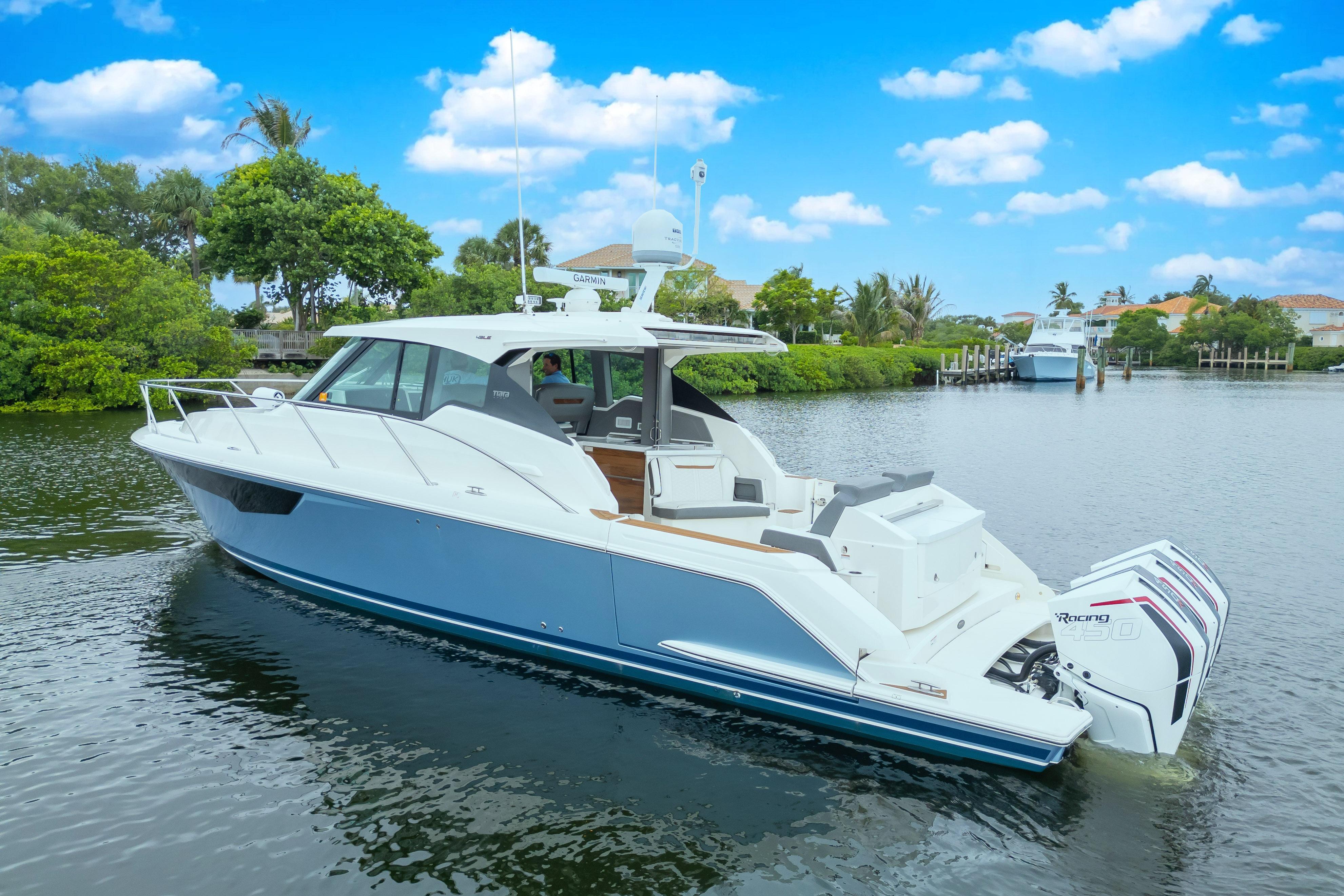 2021 Tiara Sport 43 LE boat on calm water, surrounded by lush greenery and blue sky.