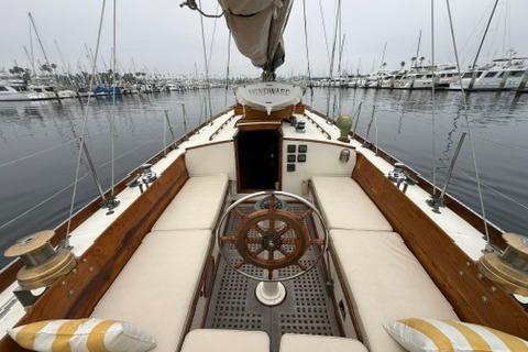 1962 Lapworth Sloop sailboat interior with wooden helm, docked in a marina.