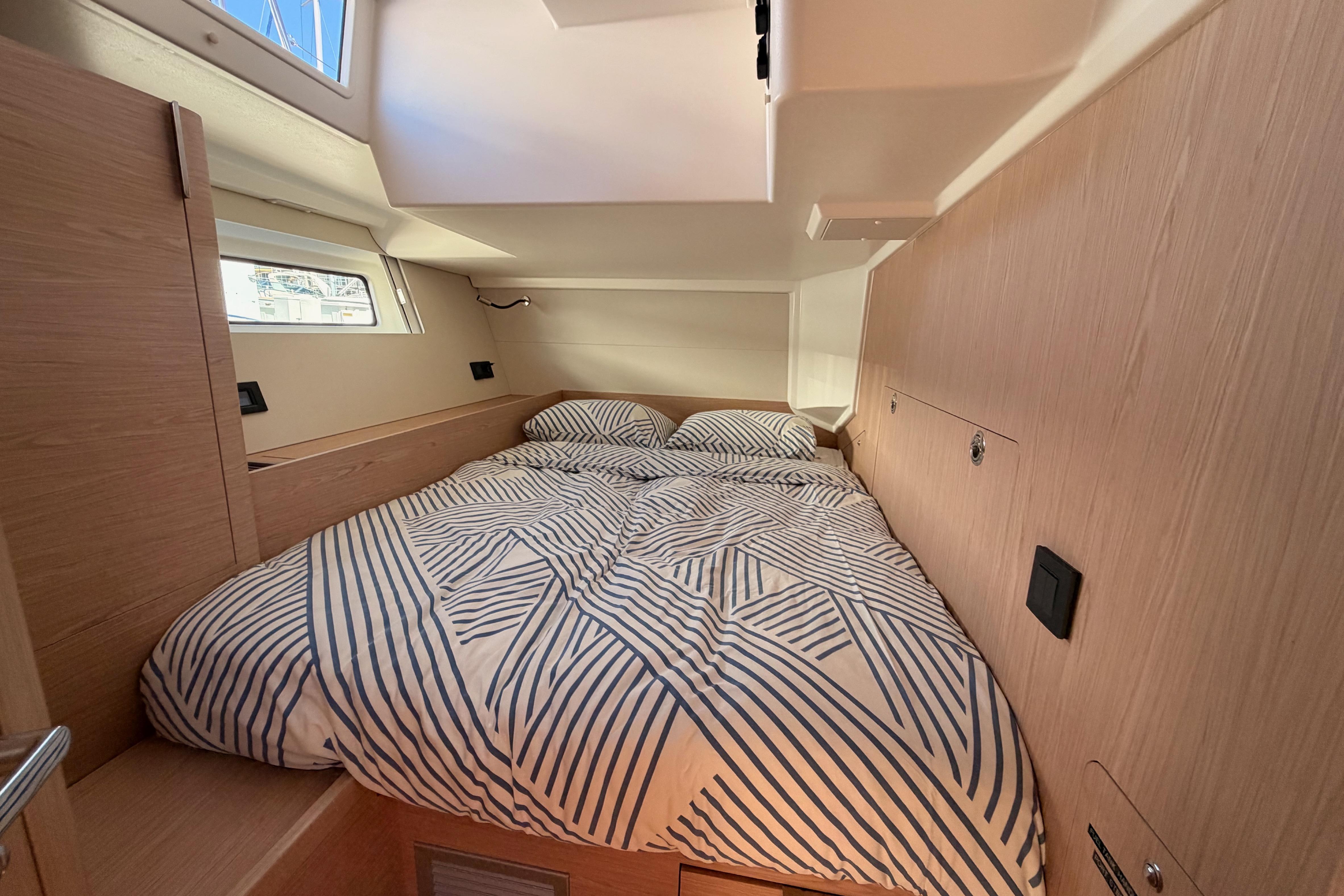 Cozy cabin interior of 2022 Beneteau Oceanis Yacht 54 with striped bedding.