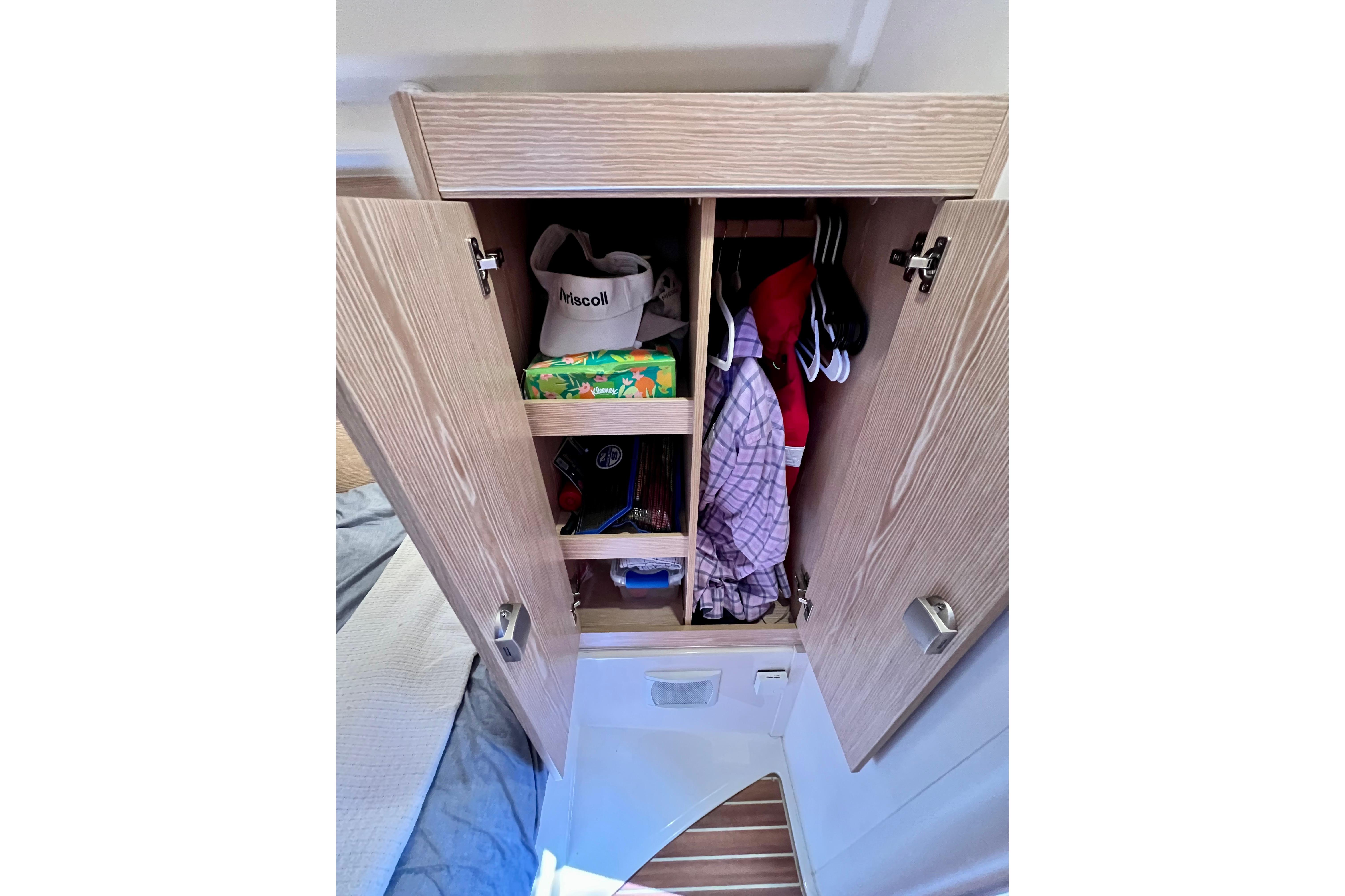 Open wooden wardrobe on 2016 Hanse 455 yacht, storing clothes and accessories.