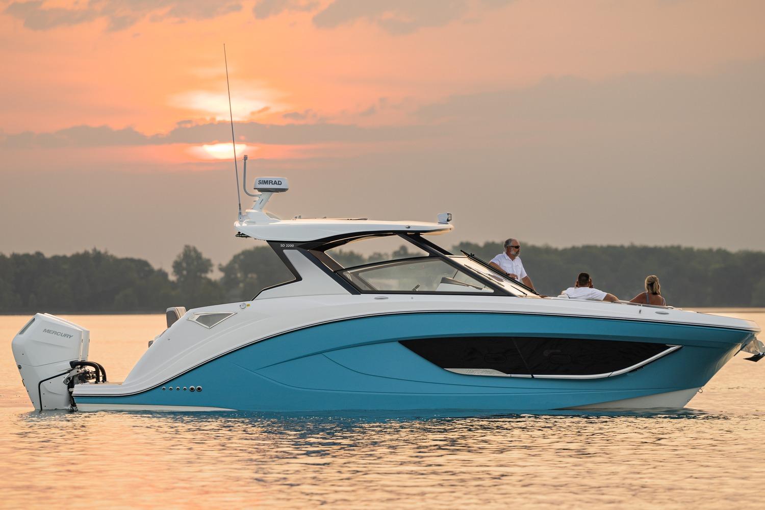 2026 Hurricane SunDeck 3200 OB boat cruising at sunset on calm waters.