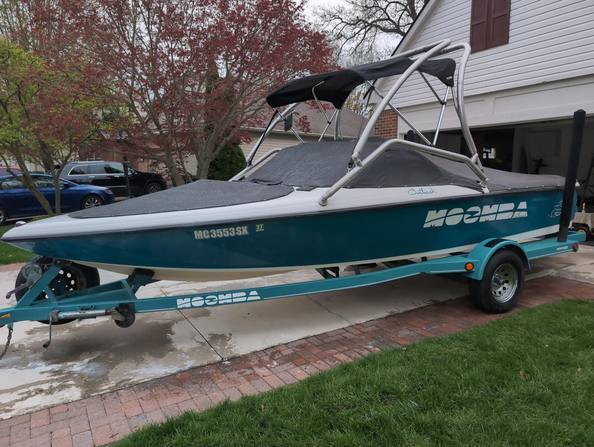 A 2000 Moomba Ouback LS boat on a trailer in a driveway.