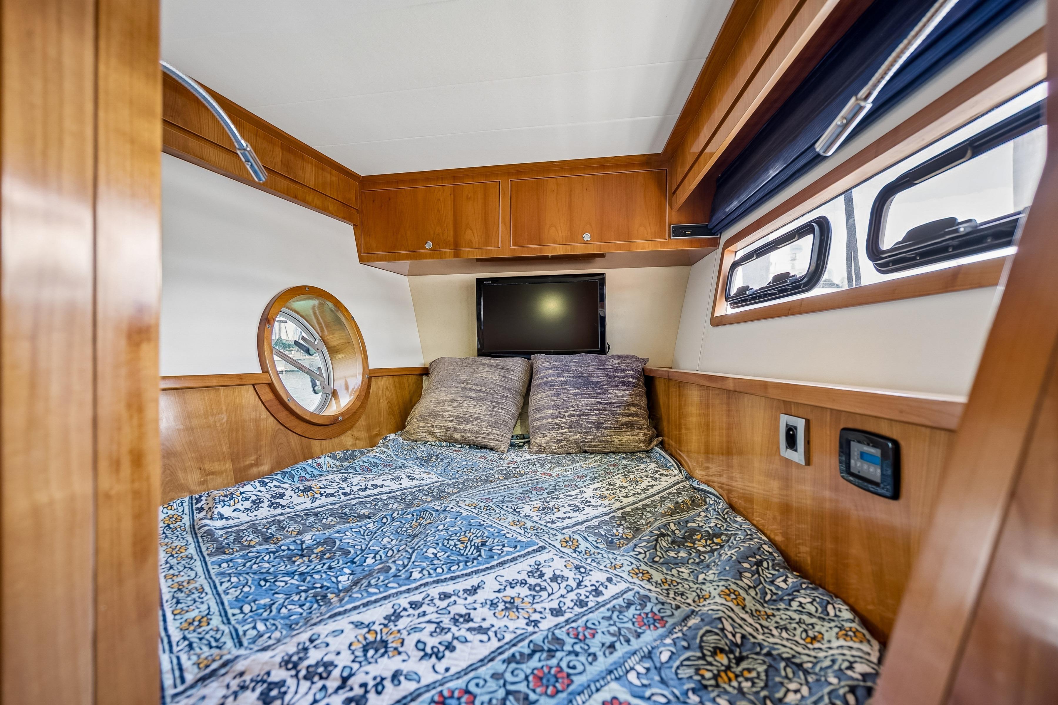 Cozy cabin interior of 2009 Catana 65 yacht with wooden accents and patterned bedding.