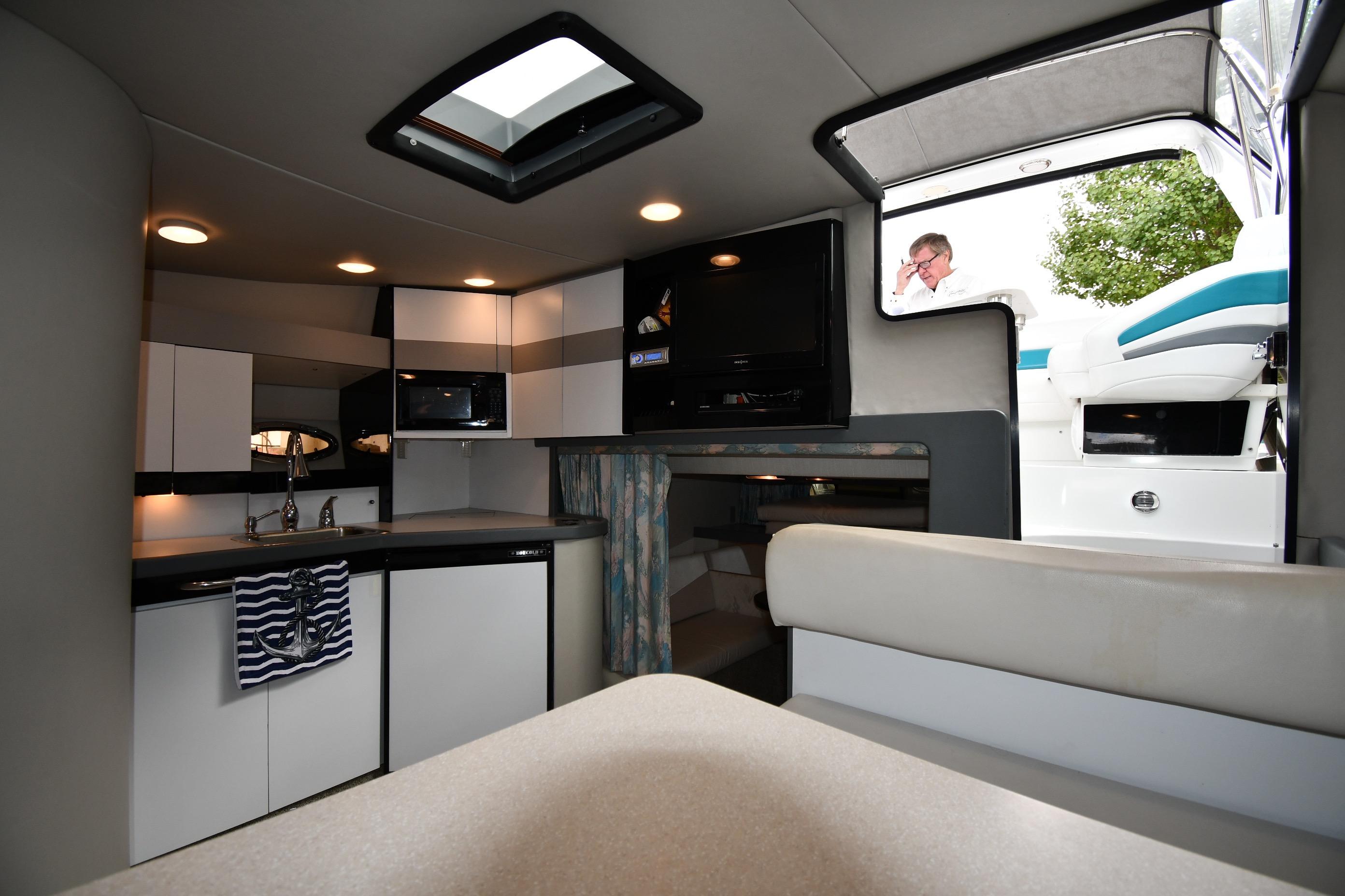 Interior of a 1990 Formula boat with kitchenette and seating area.