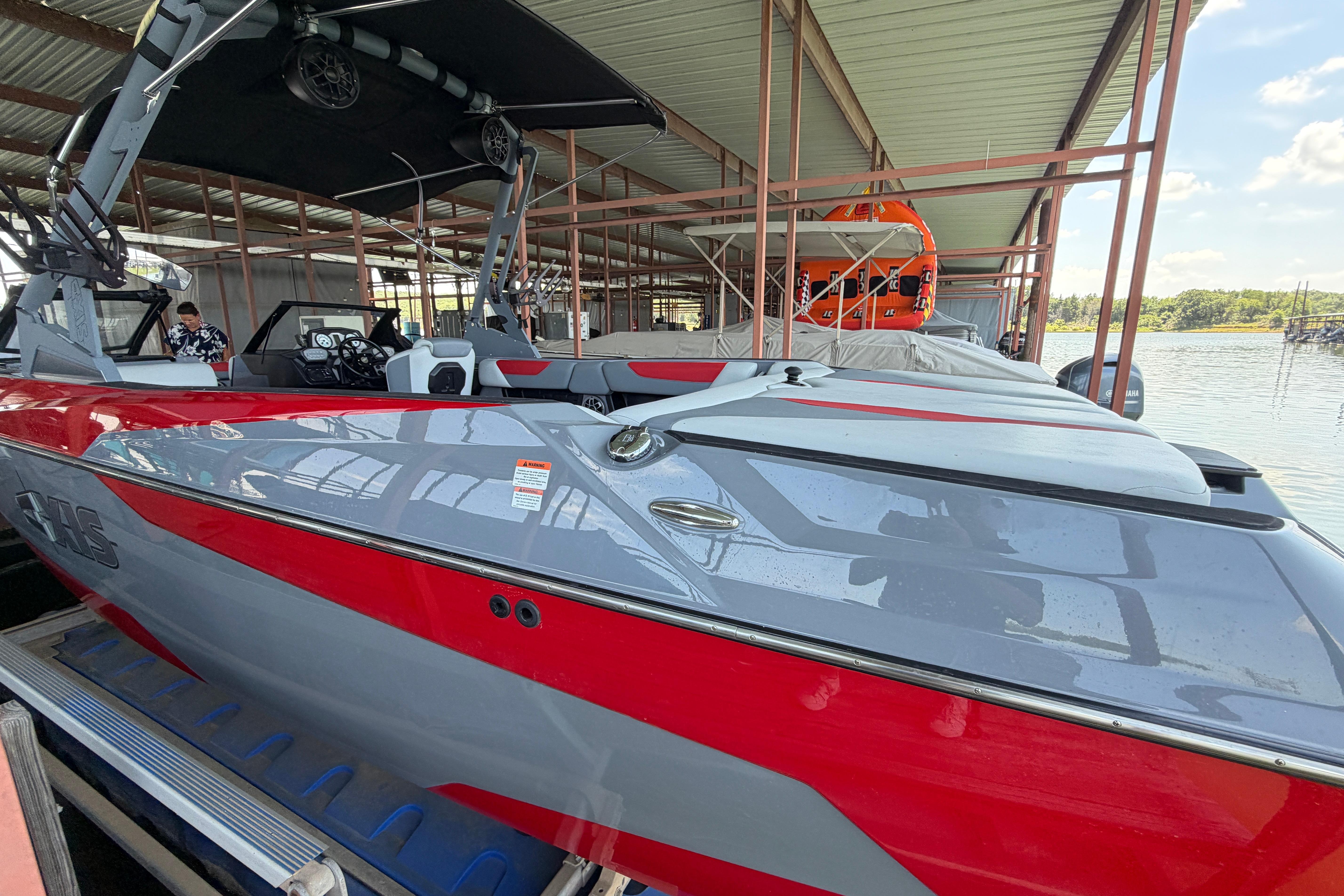 2021 Axis A24 boat in dock, featuring sleek red and gray design under a covered structure.