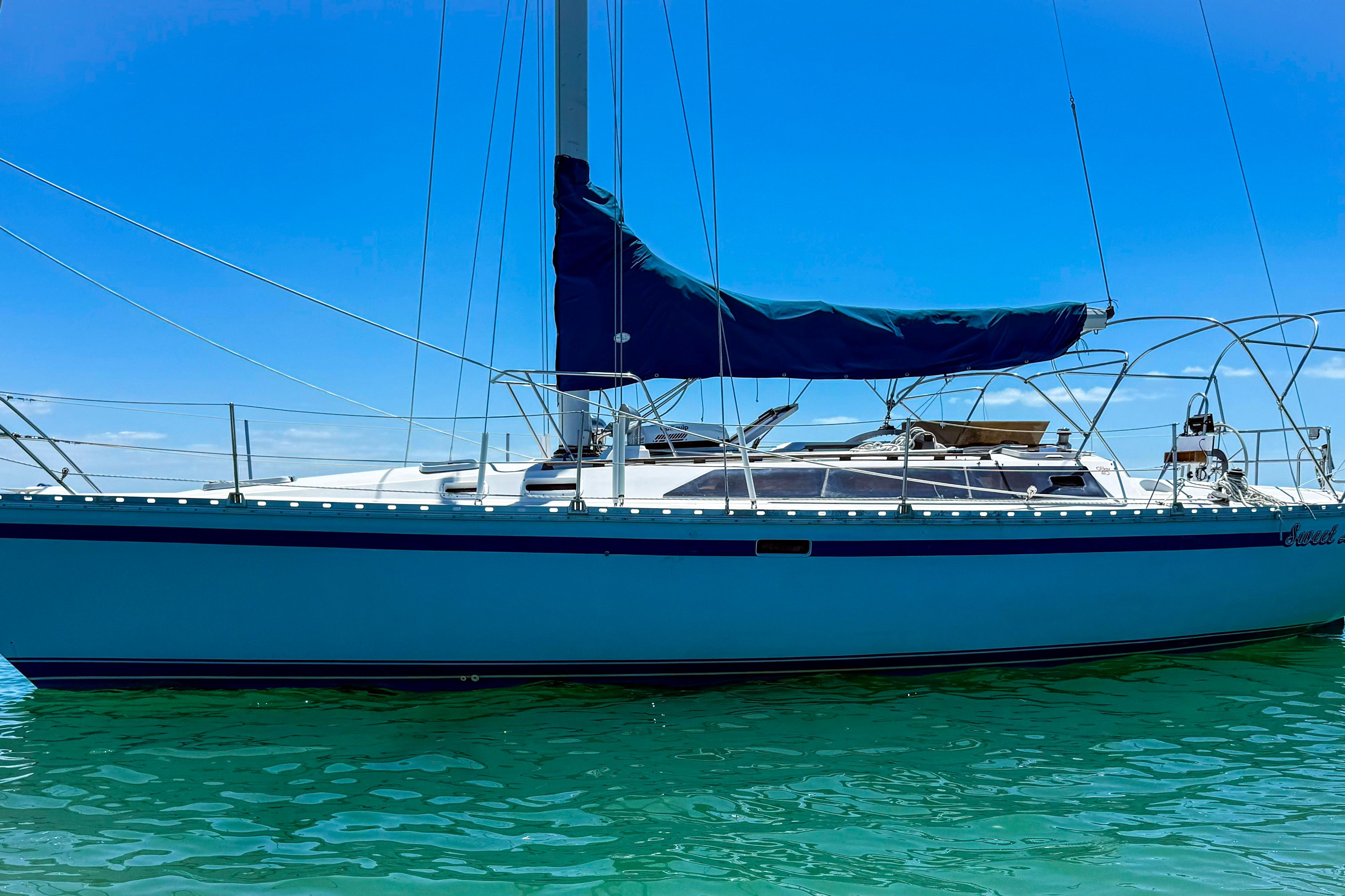 1988 Oday 40 sailboat on clear turquoise water under a bright blue sky.