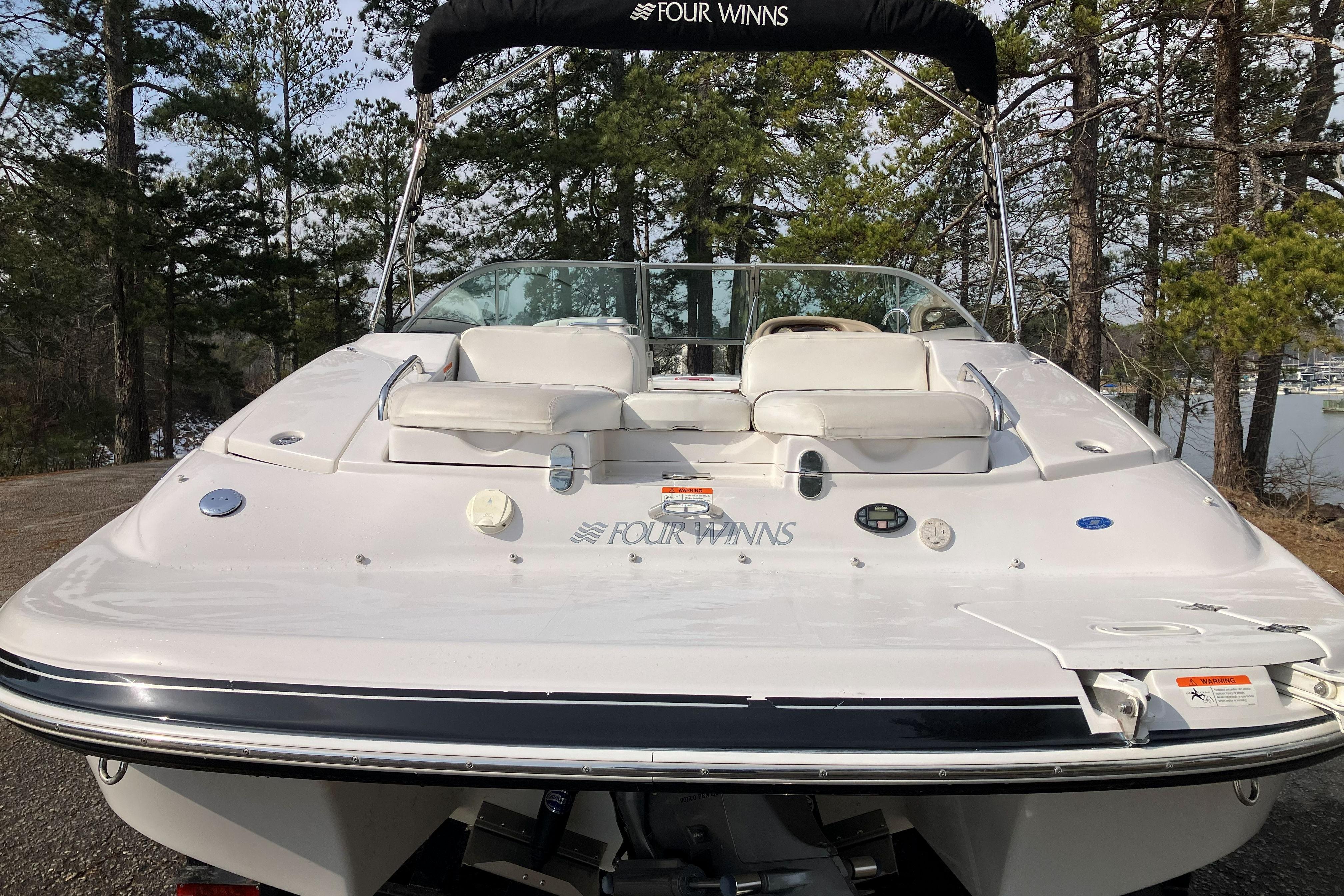 2006 Four Winns 240 Horizon boat with white seating, docked near a forested lake.
