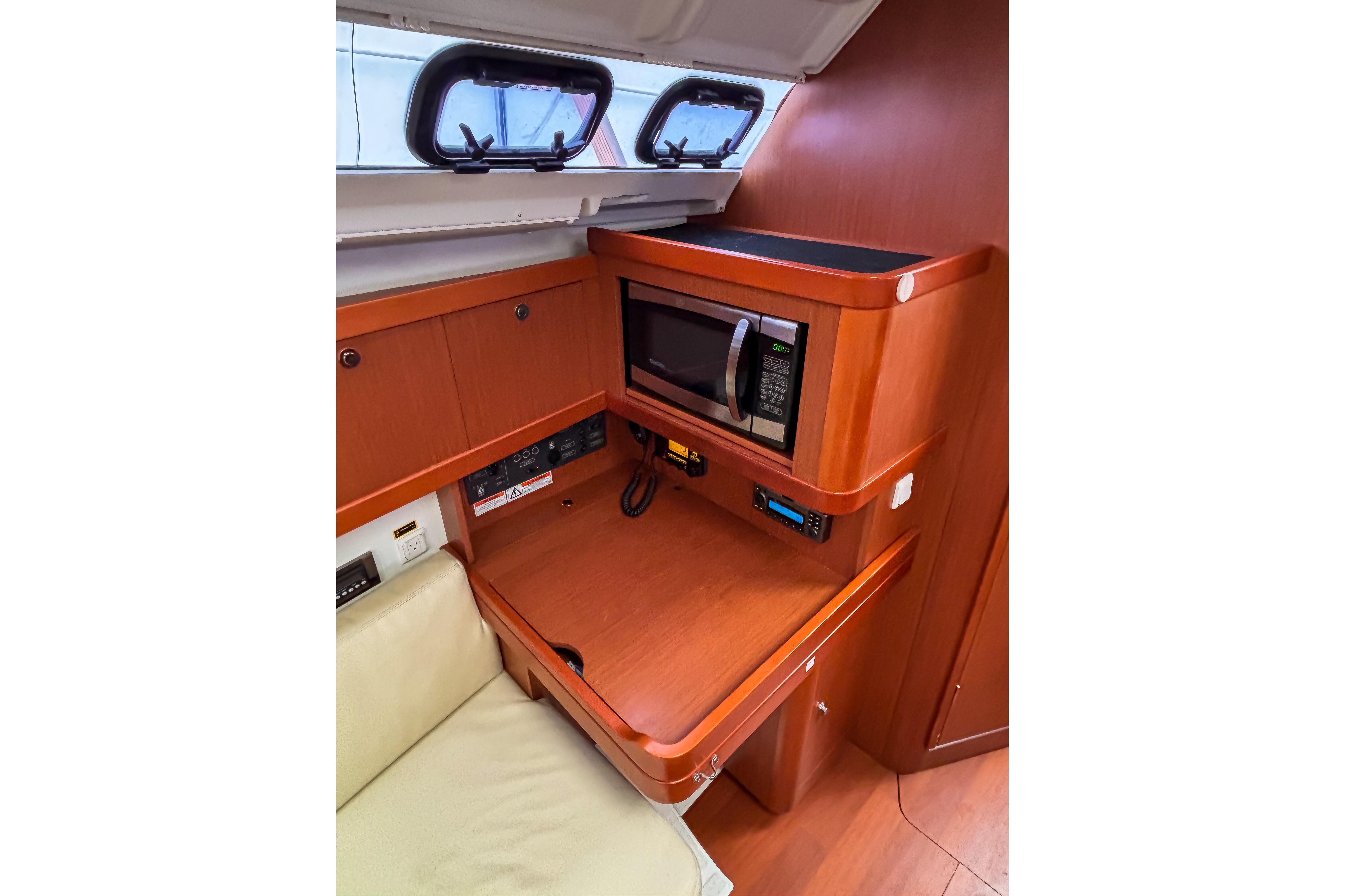 Interior of 2015 Beneteau Oceanis 37 yacht with microwave and wooden cabinetry.