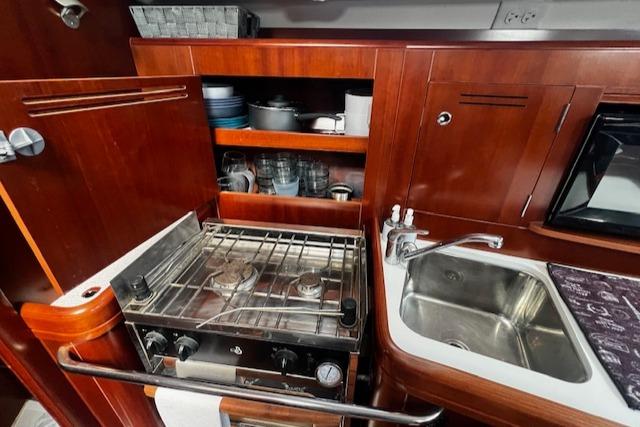 2006 Beneteau 343 Sloop kitchen with stove, sink, and wooden cabinetry.