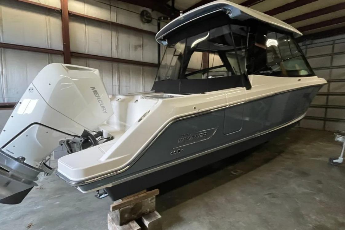 2025 Boston Whaler 330 Vantage boat with Mercury engine in a warehouse.