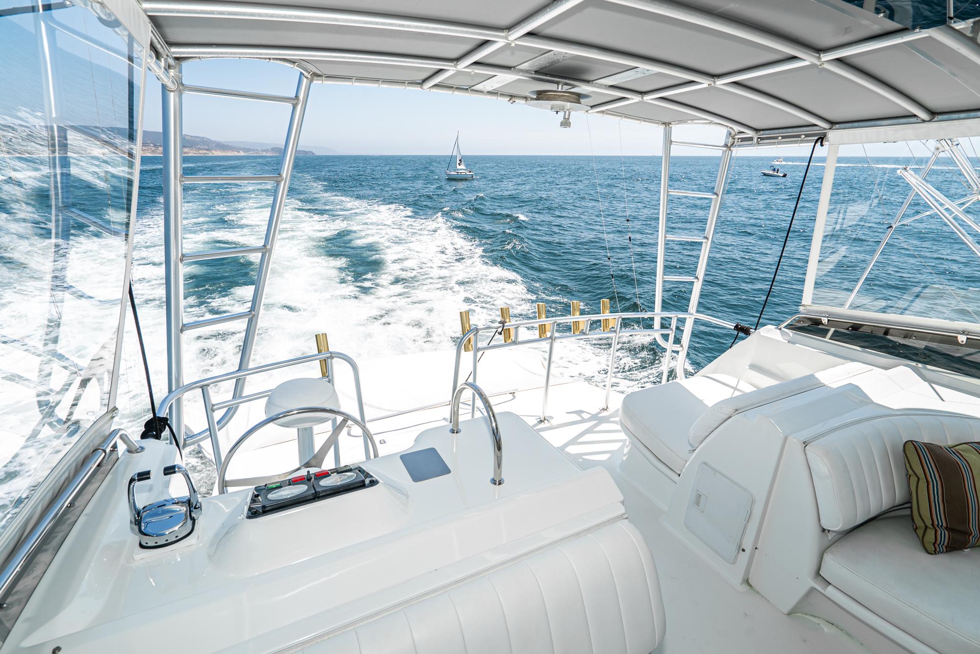 1990 Hatteras 58 Sportfish yacht interior with ocean view, featuring white seating and helm controls.