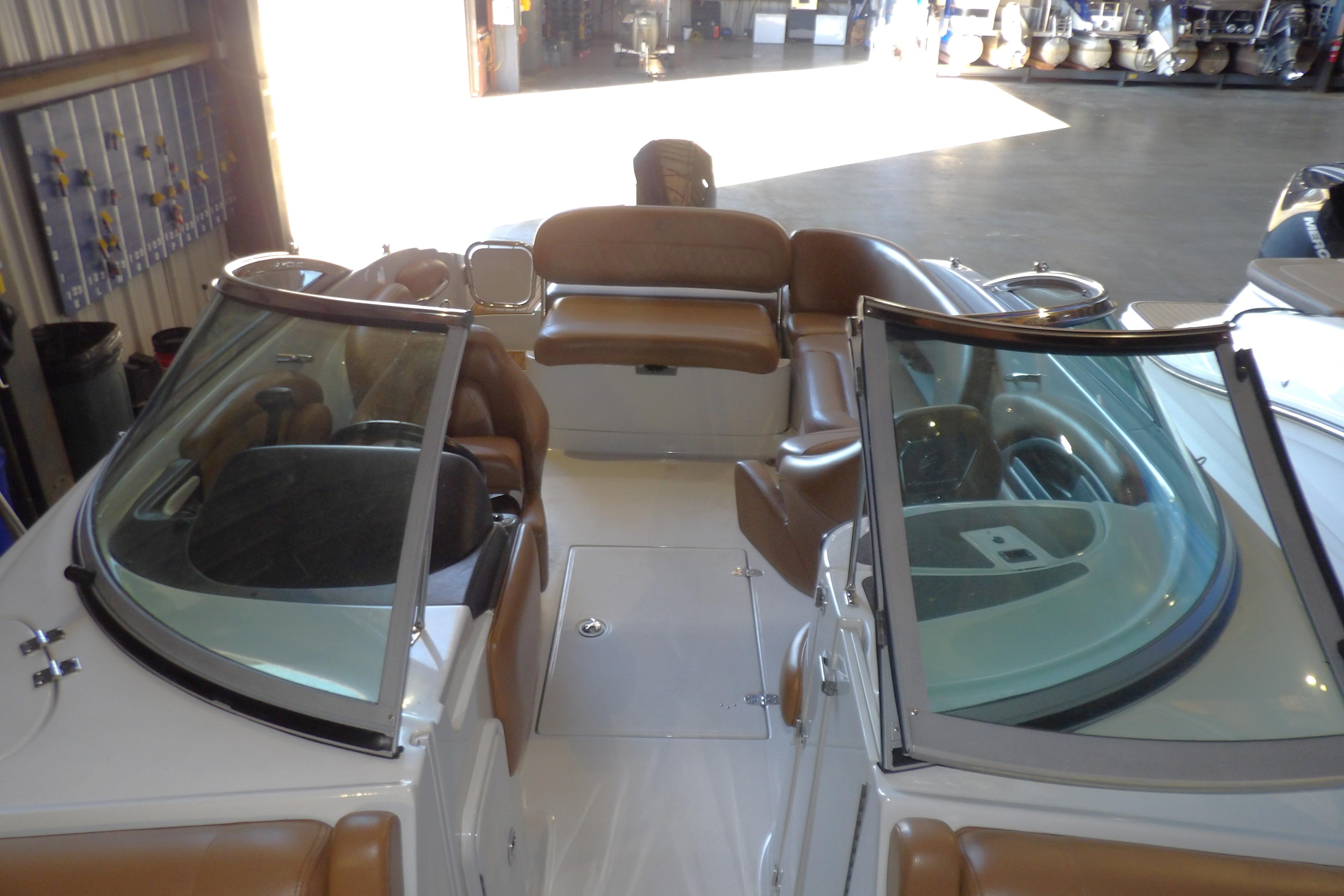 2023 Crownline 250 XSS boat interior with brown seating and dual windshields in a showroom.