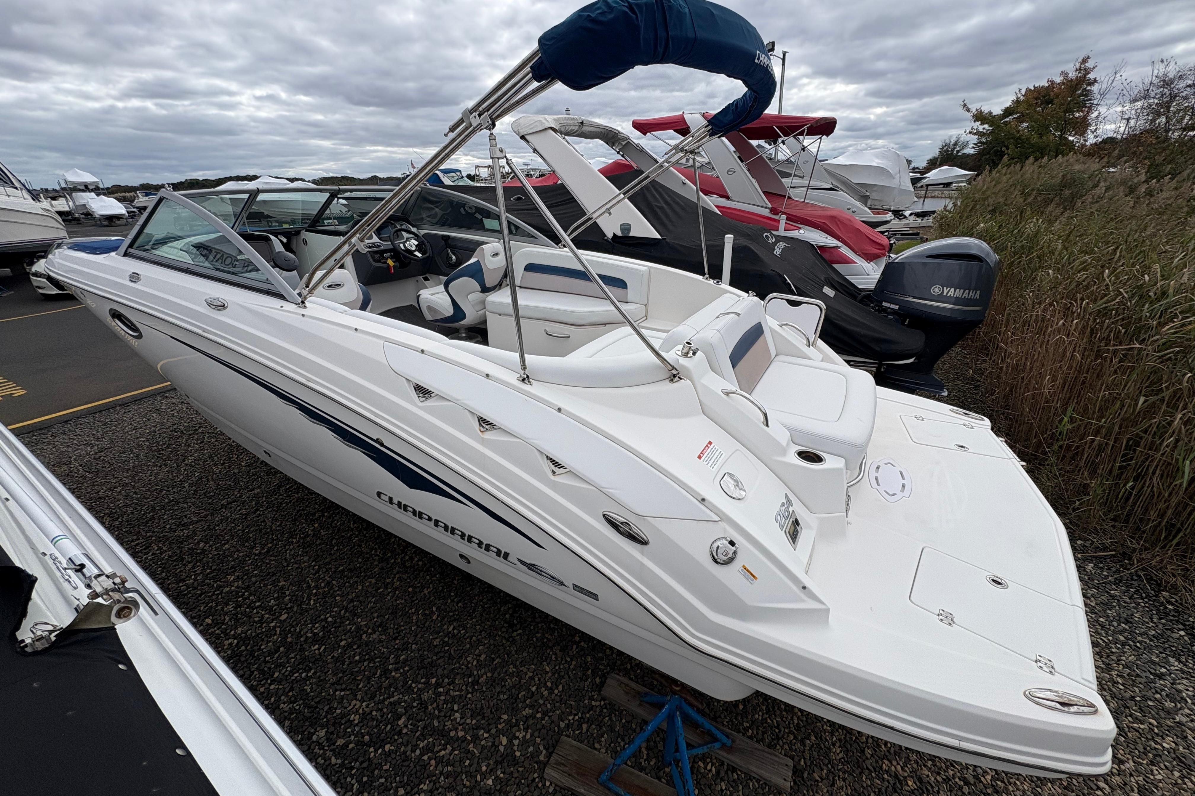 2015 Chaparral 264 Sunesta boat with sleek design, docked outdoors under cloudy skies.