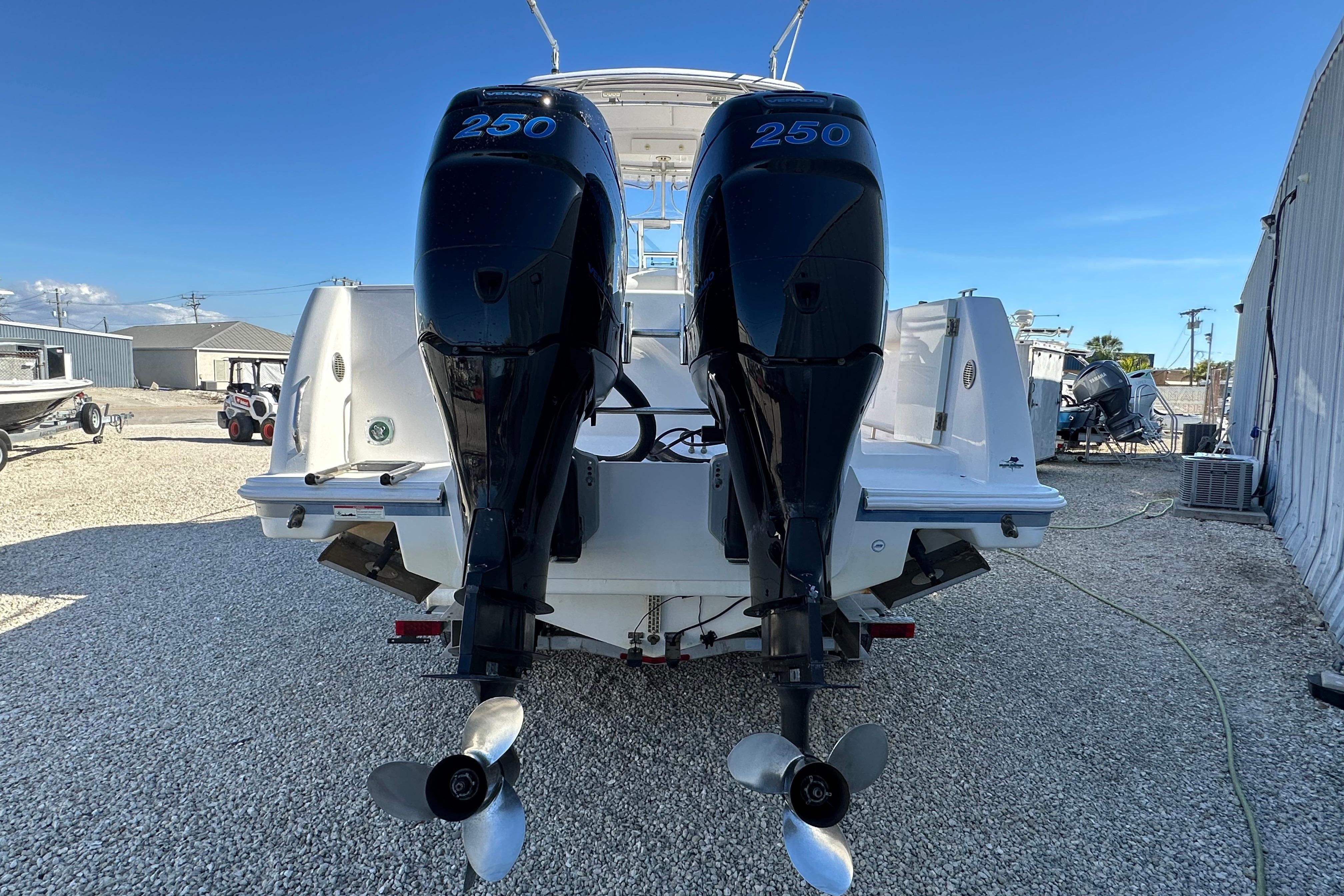2006 Pro-Line 32 Express boat with twin 250 horsepower outboard engines, parked on gravel.