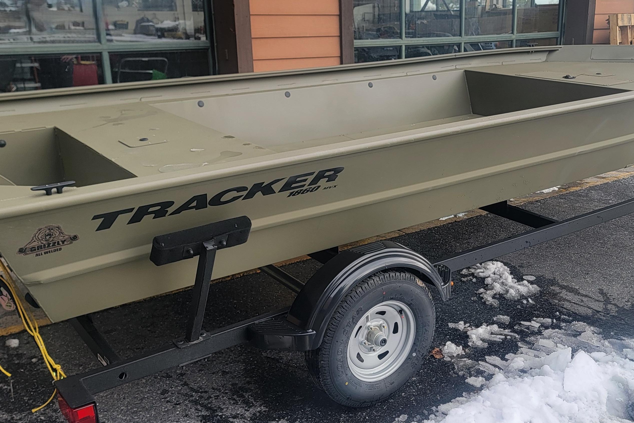 2026 Tracker Grizzly 1860 Utility boat on trailer, parked on snowy pavement.