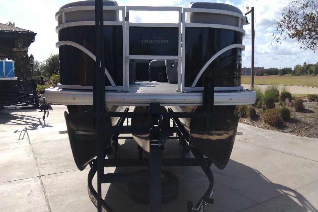 2026 Sun Tracker SportFish 22 XP3 pontoon boat on a trailer, parked outdoors.