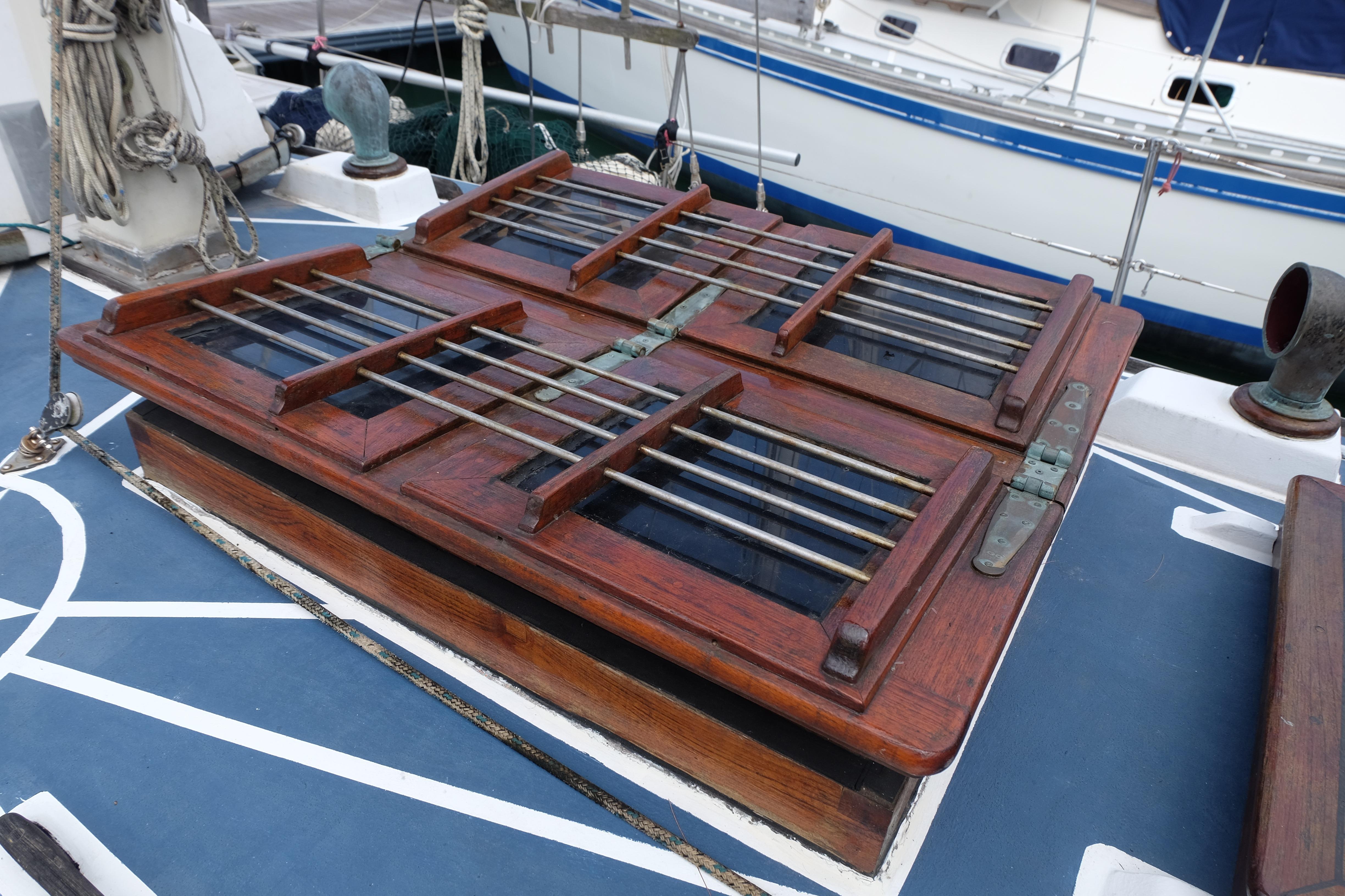Wooden hatch on 1979 Westwind 35 sailboat deck, featuring metal bars and hinges.