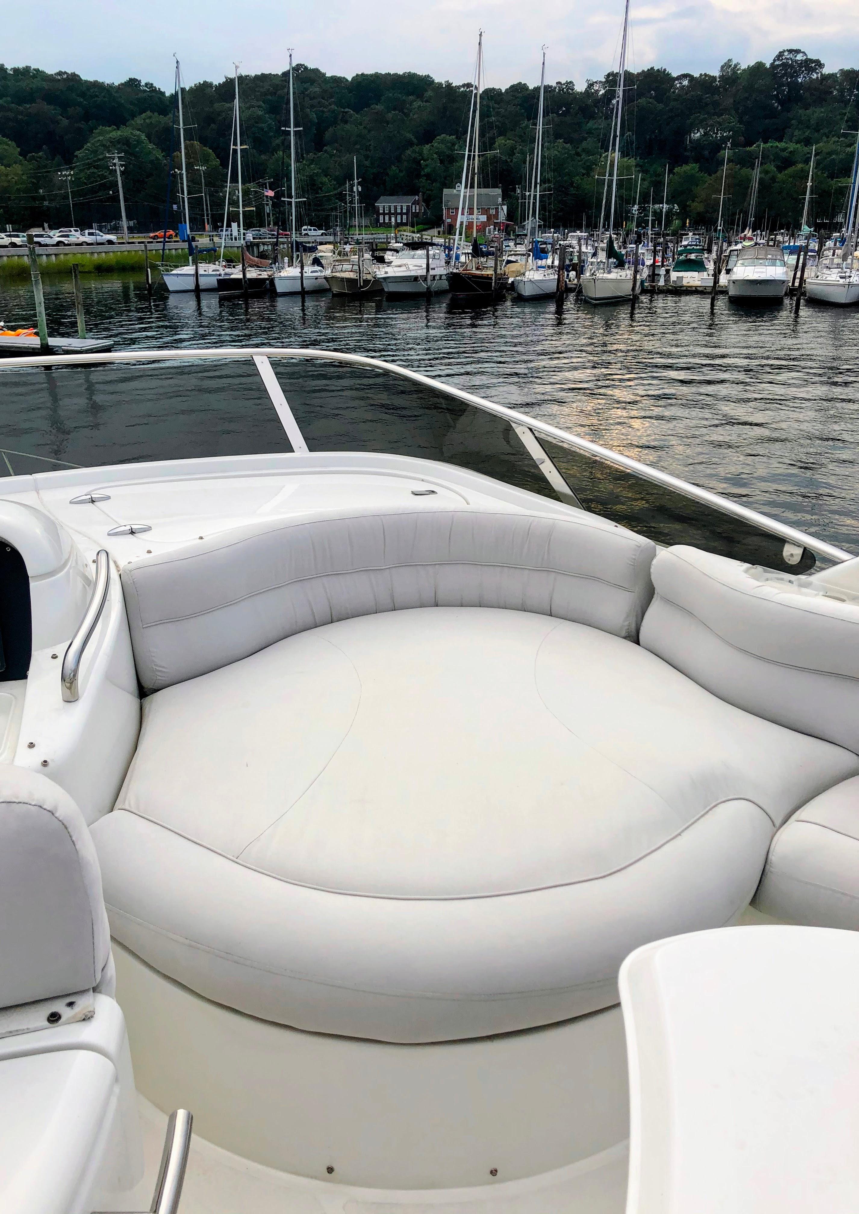 Luxurious 2002 Azimut 55 yacht with spacious white seating, docked in a scenic marina.