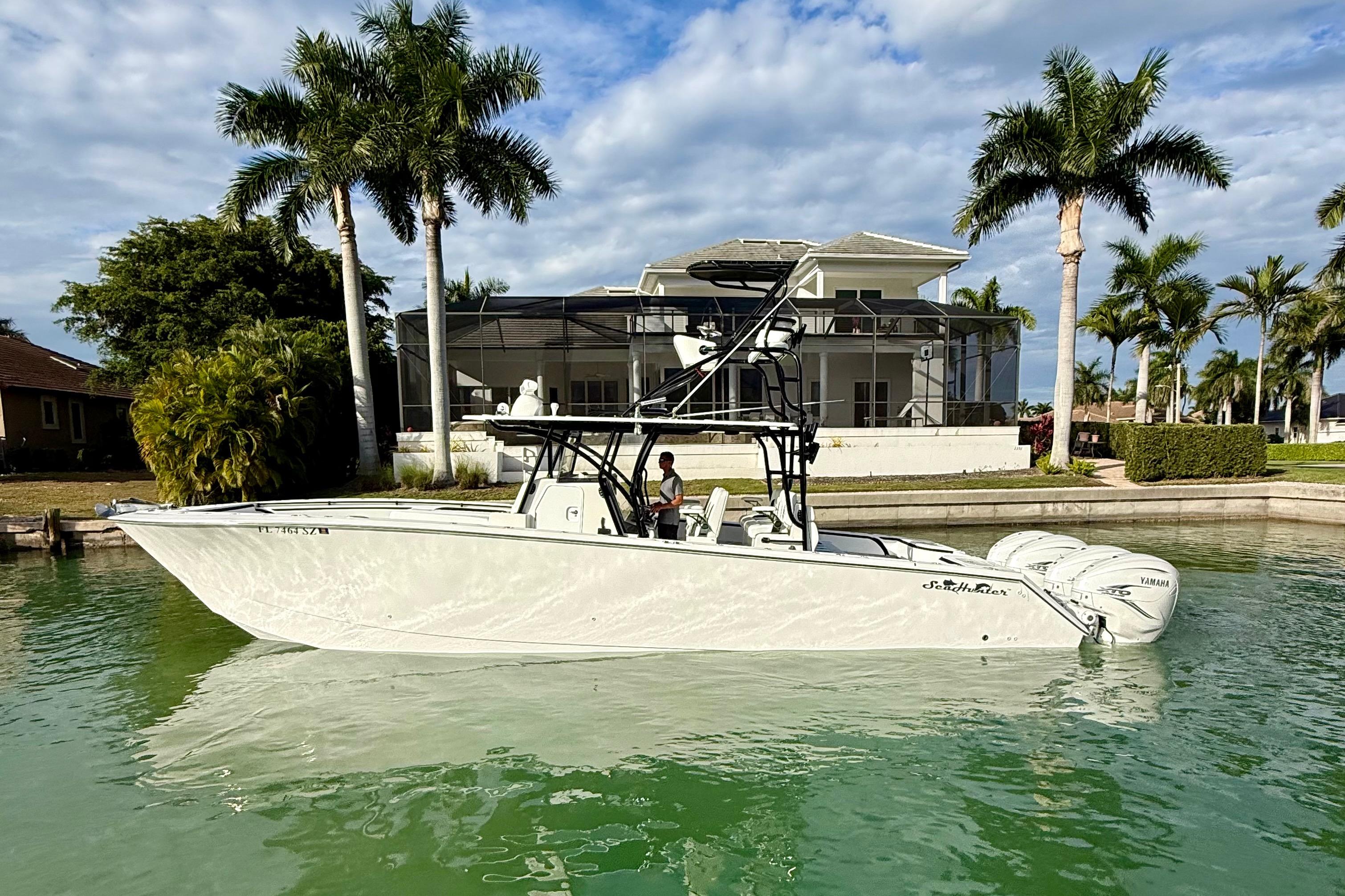 2020 SeaHunter 41 CTS boat on water, near a waterfront home with palm trees.