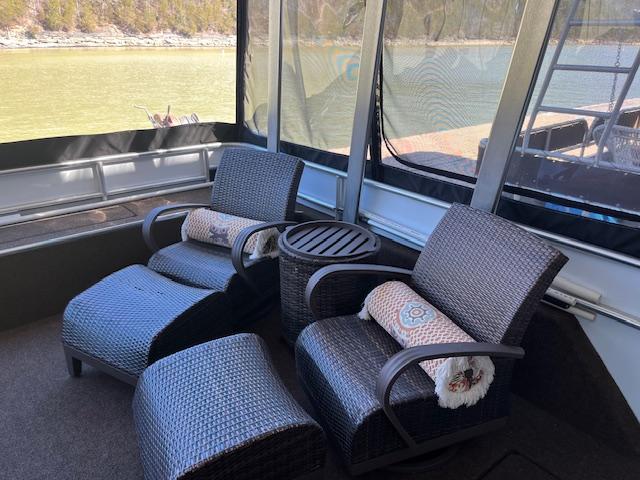 Cozy seating area on 2013 Thoroughbred houseboat with wicker chairs and scenic lake view.
