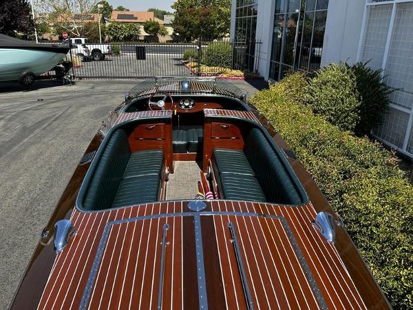 1994 Hacker-Craft 26' Runabout with polished wood finish and green interior, parked outdoors.