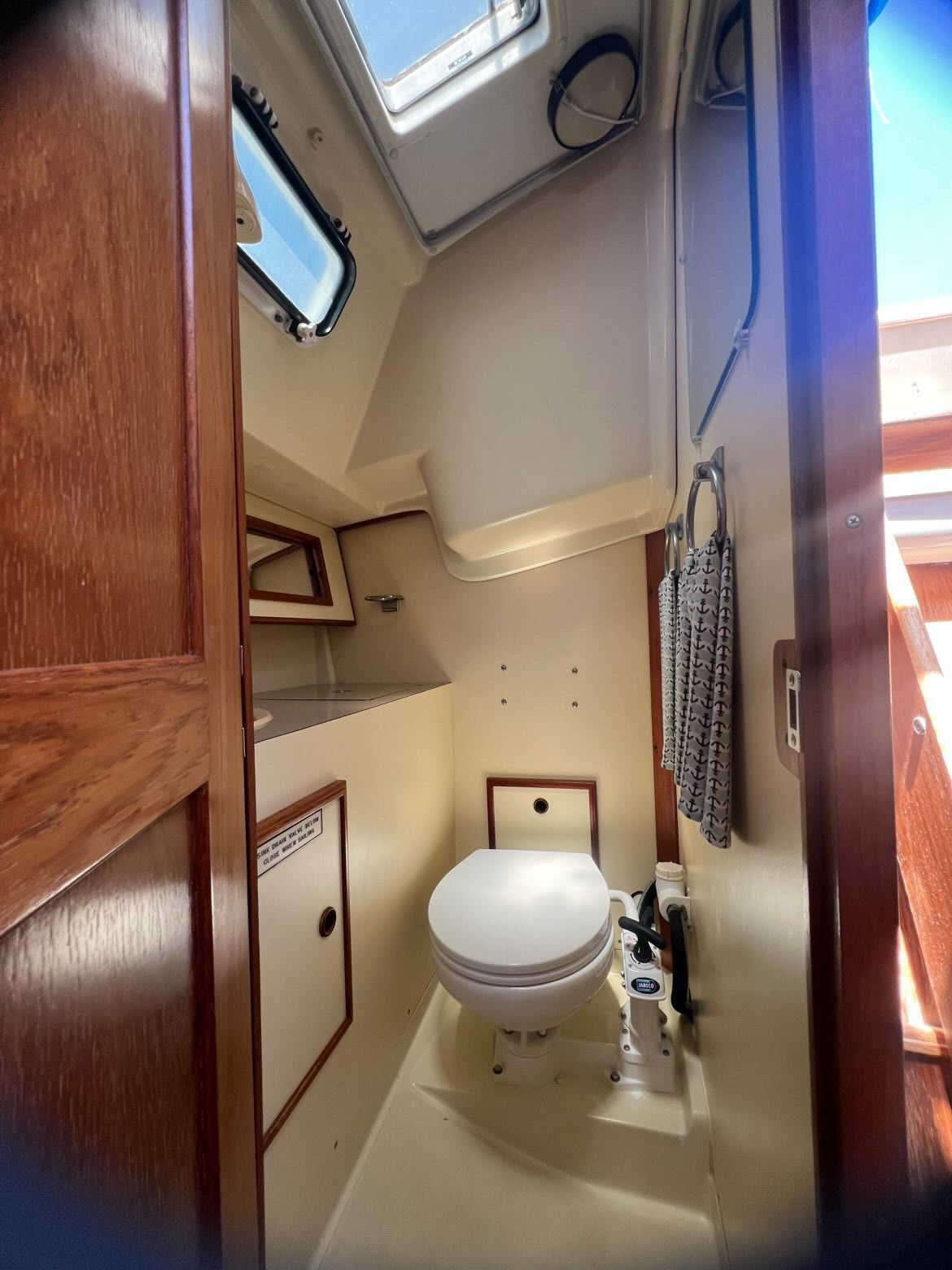 Interior view of a boat bathroom with toilet, sink, and wood paneling.