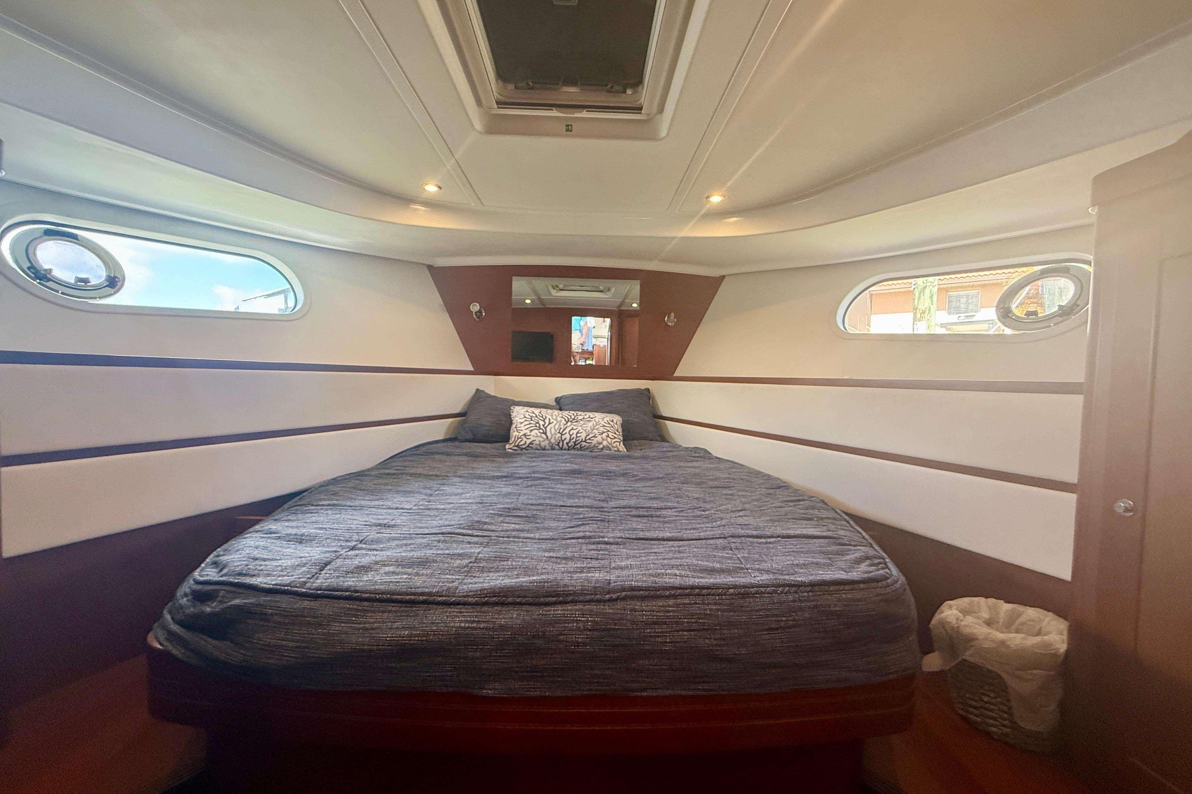 Interior cabin of 2020 Beneteau Swift Trawler 44 with cozy bed and porthole windows.