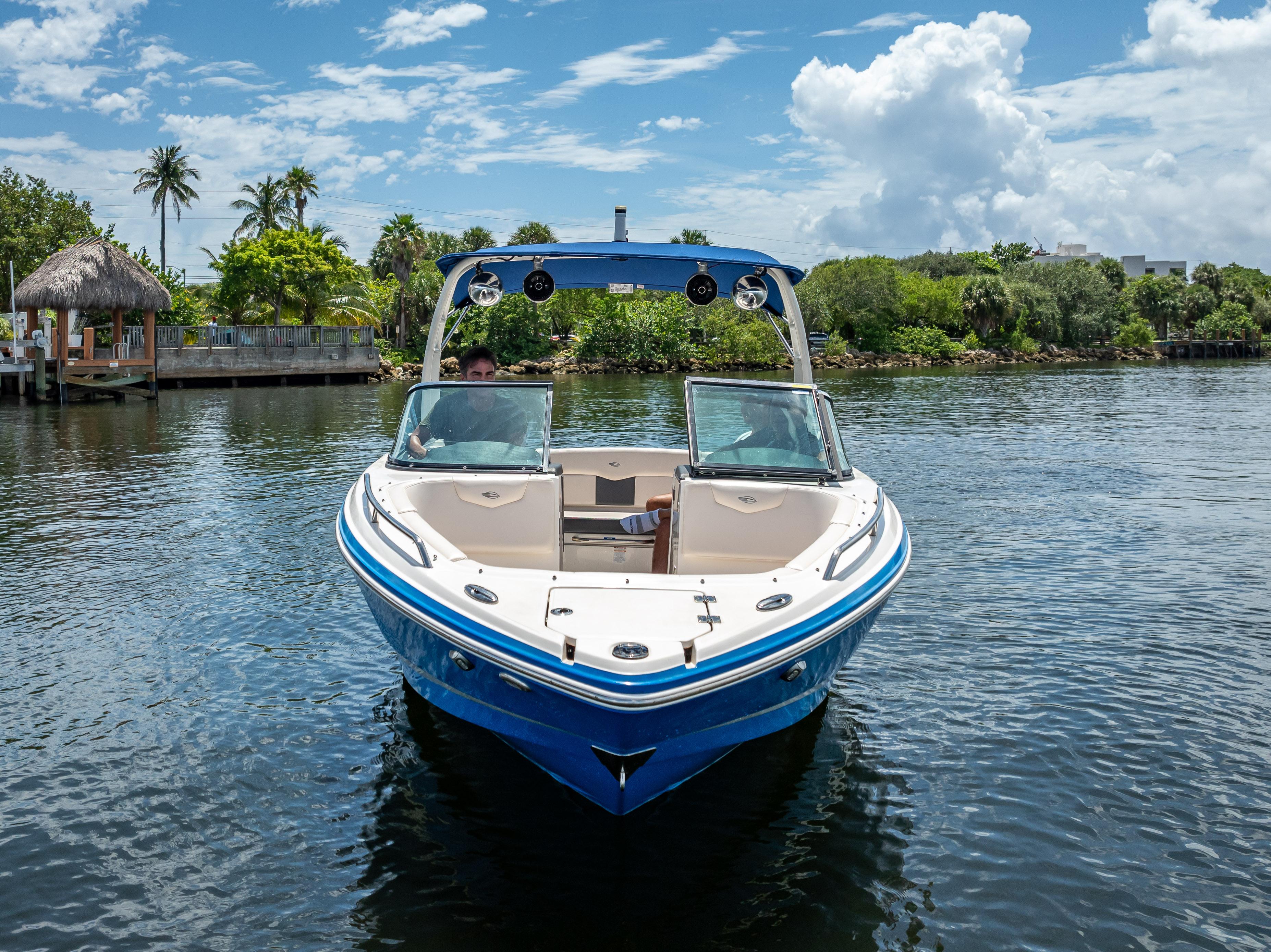 2017 Chaparral 227 SSX boat on a sunny day, surrounded by lush greenery.