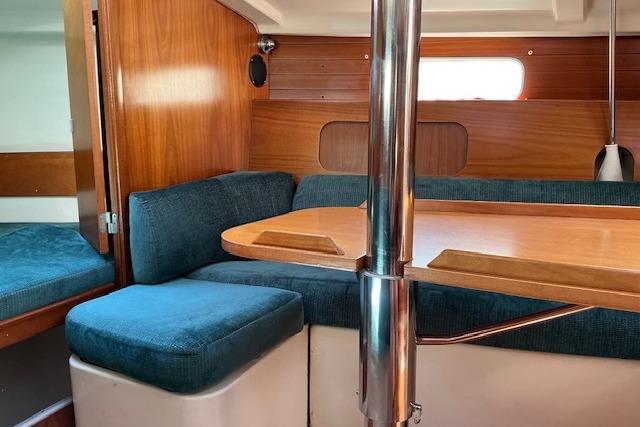 Interior of 2000 Beneteau Oceanis 321 sailboat with wooden finish and blue seating.