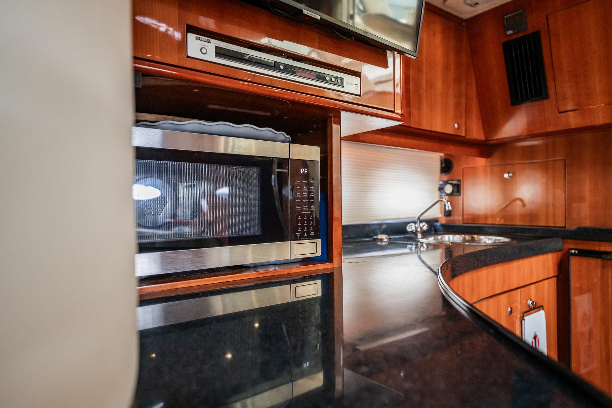 2008 Regal Commodore 4460 yacht interior with microwave, sink, and wooden cabinetry.